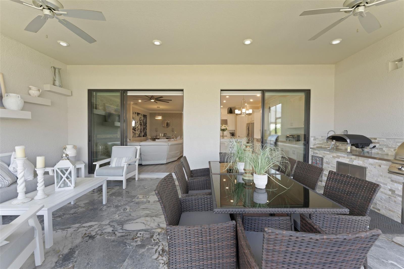 The outdoor living area is customized with a finished floor, outdoor kitchen with a grill and sink, and oversized for entertaining family or friends.