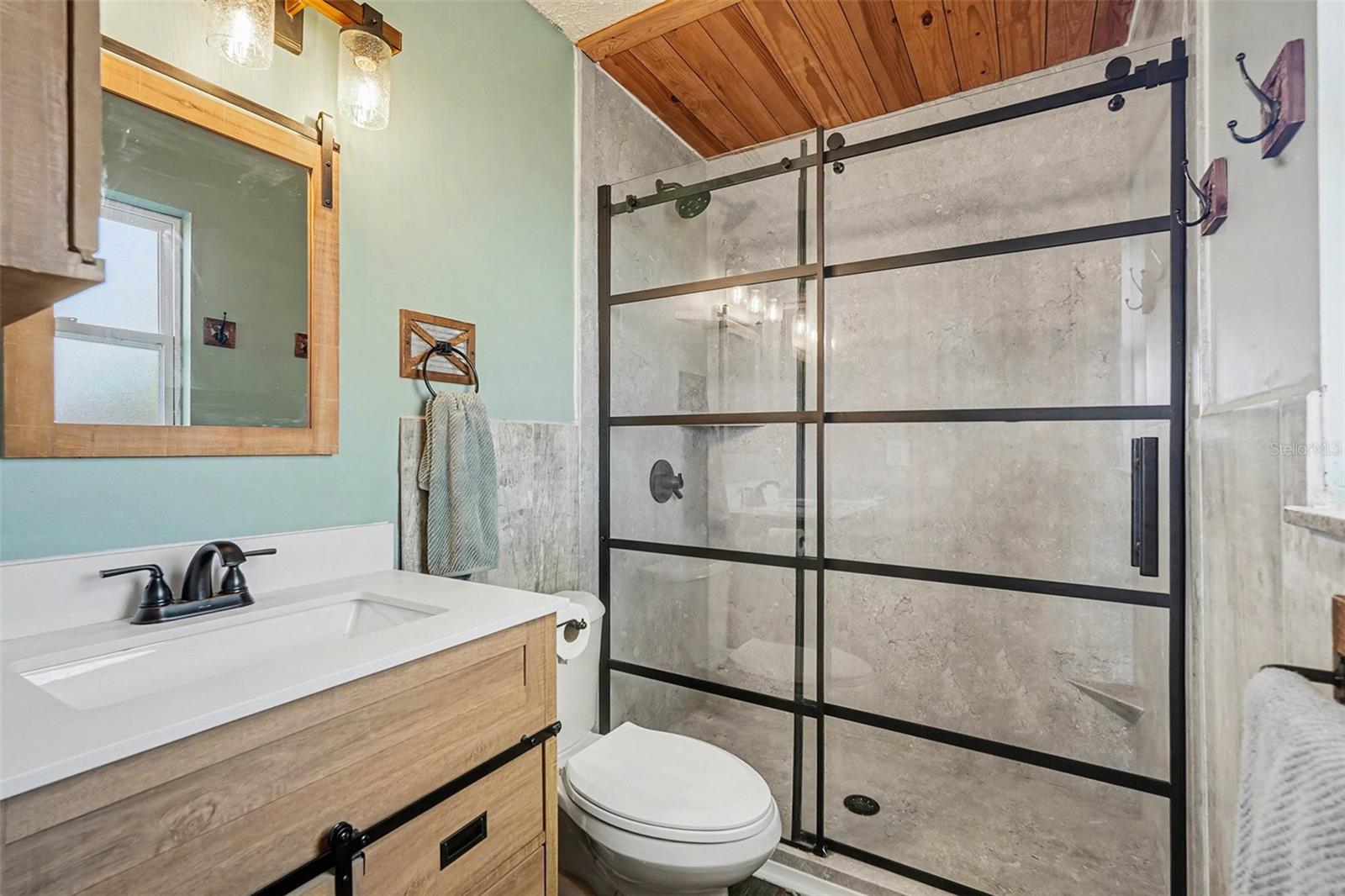 Updated bathroom featuring a custom vanity, modern fixtures, and a stylish walk-in shower with glass enclosure.