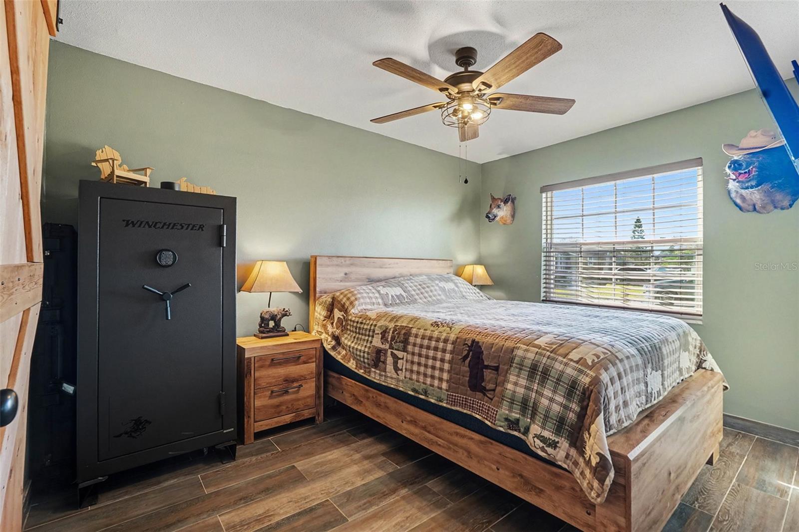 Generously sized secondary bedroom with wood-look tile flooring, ceiling fan, and bright natural light