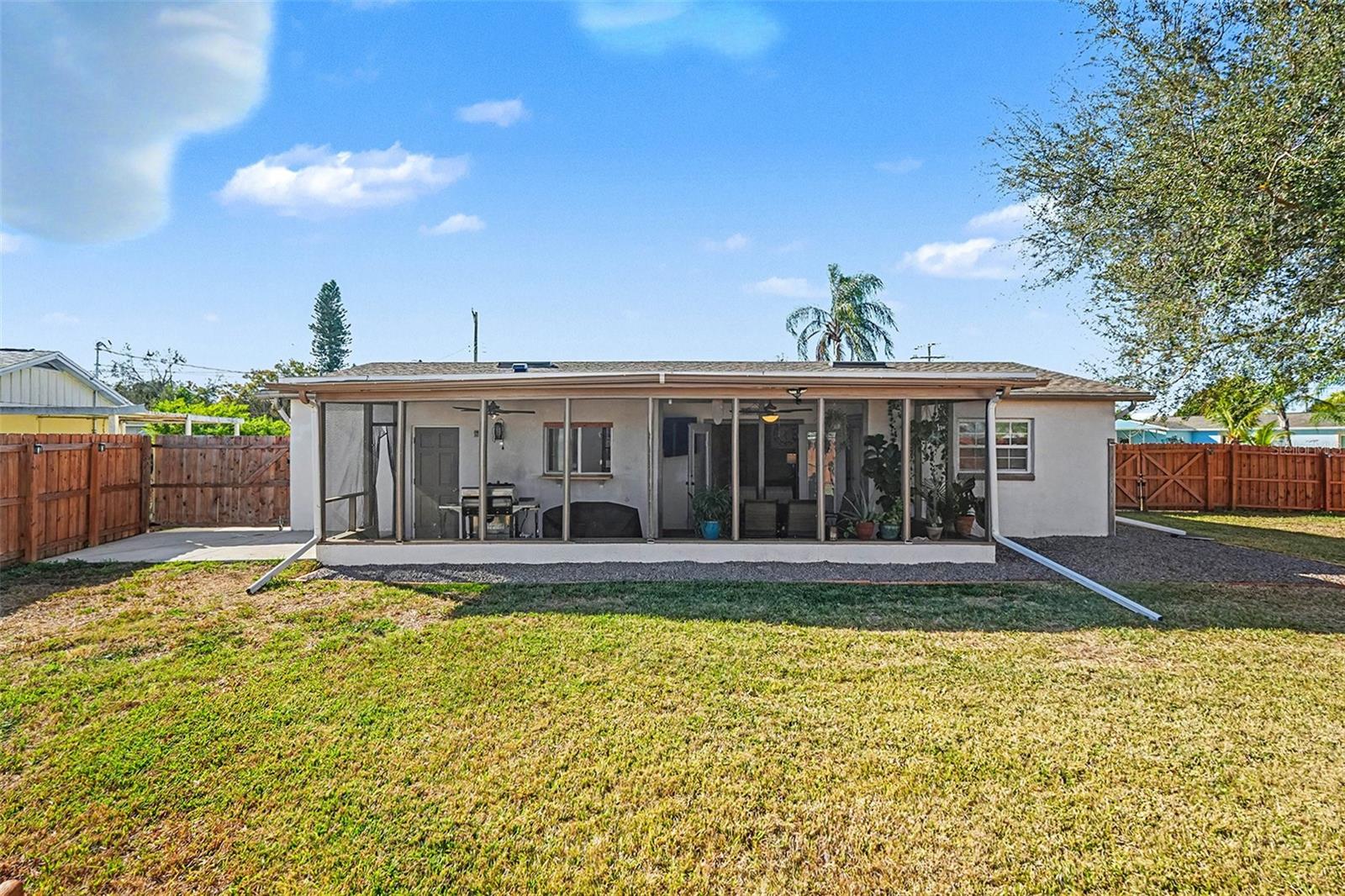 Rear exterior view showcasing the full-length screened porch and generous backyard space