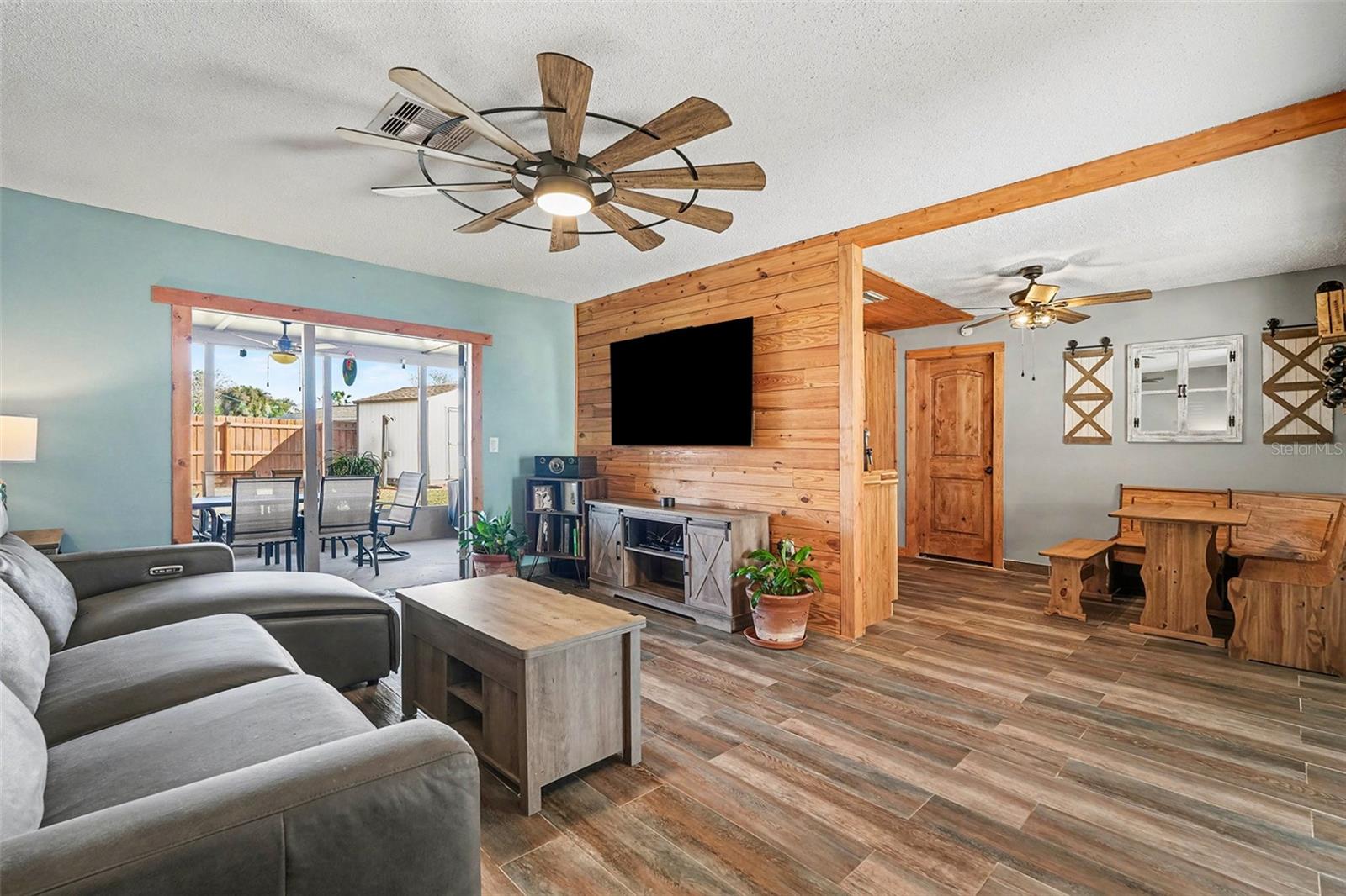Spacious living area with custom accent wall, modern lighting, and seamless indoor-outdoor connection ideal for entertaining.
