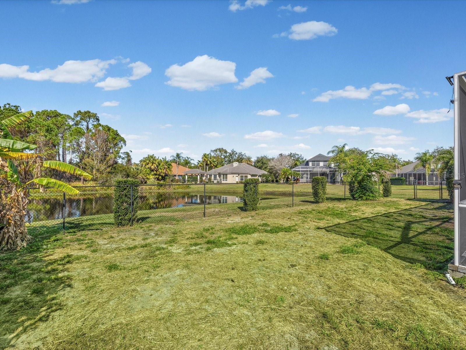 Fenced backyard with view of pond