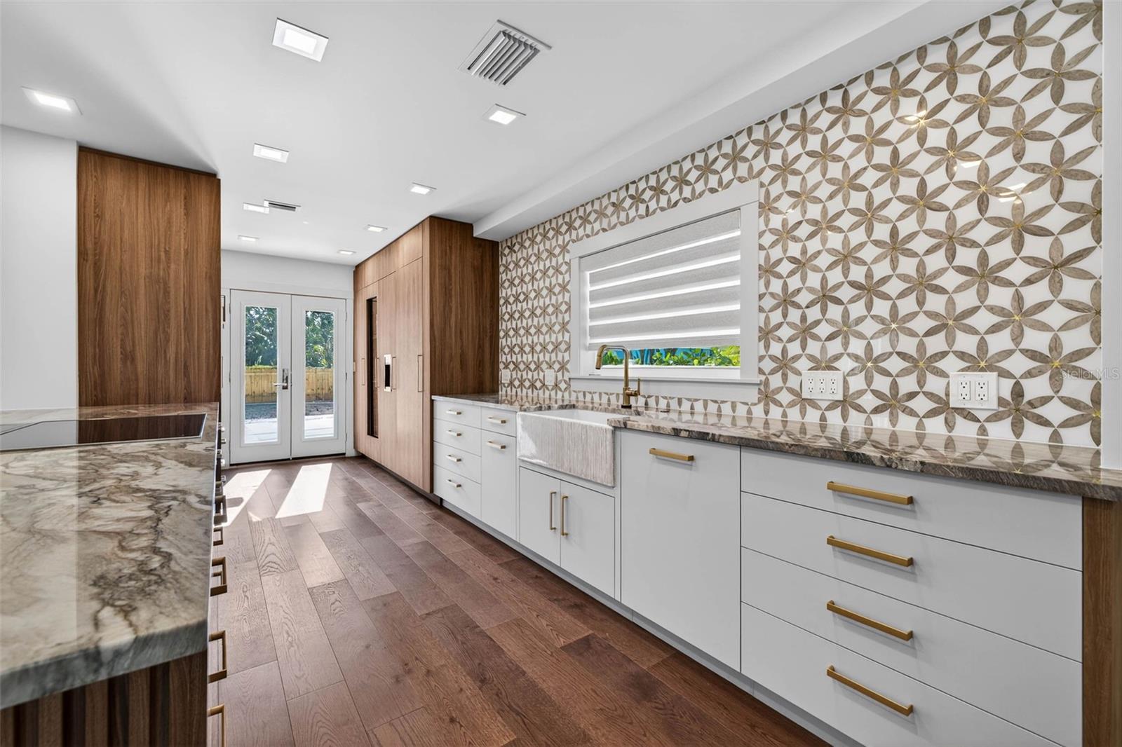 Shaw farm house sink with touchless faucet across from Miele cooktop with pop up vent.