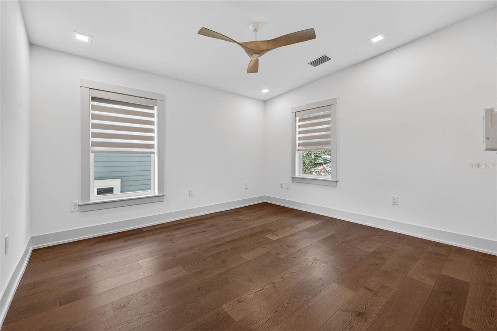 Bedroom two with custom built in closet, ceiling fan, and custom window treatments.
