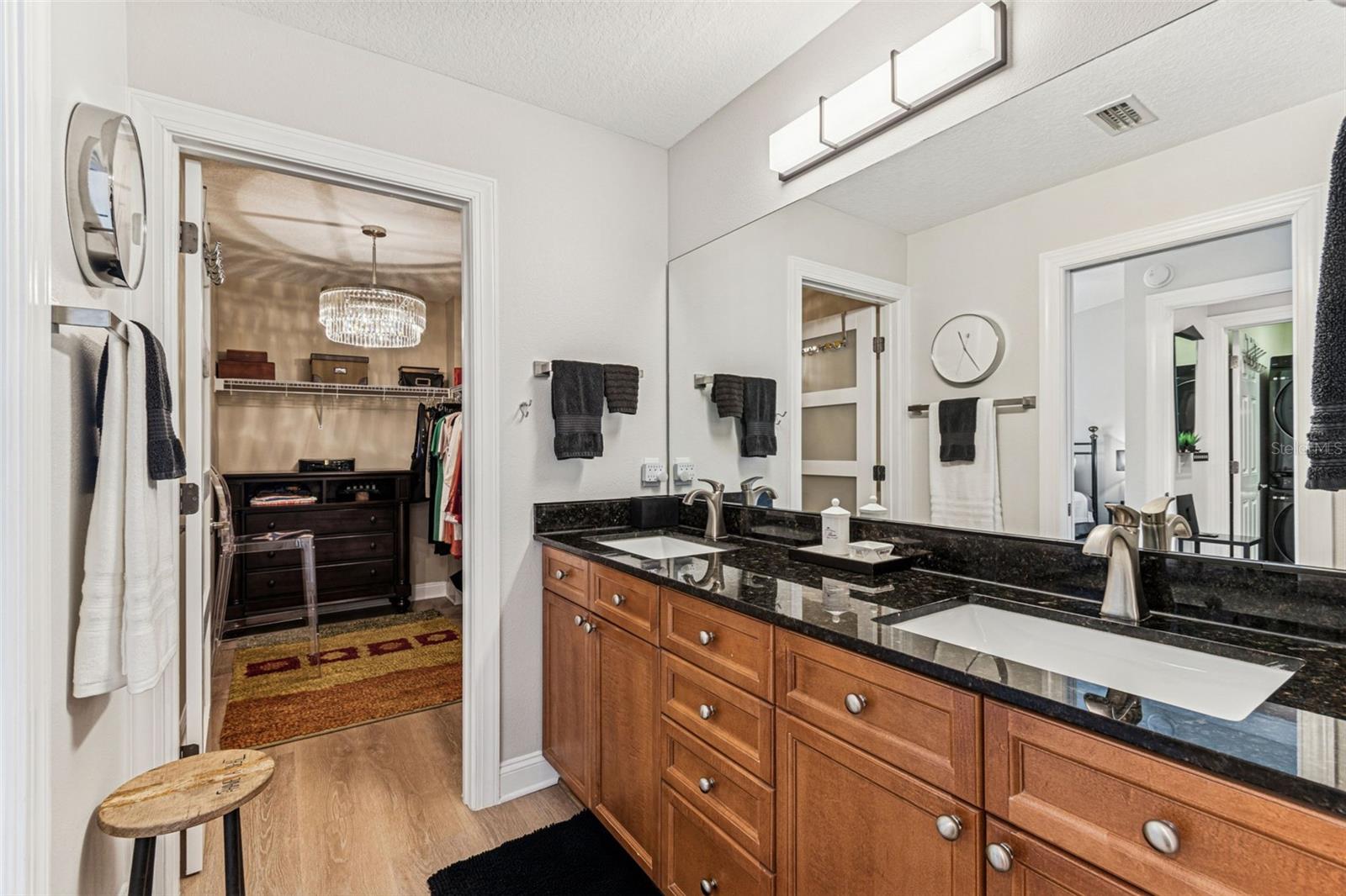 Master bath w/2 sinks and view of spacious master closet with chandelier