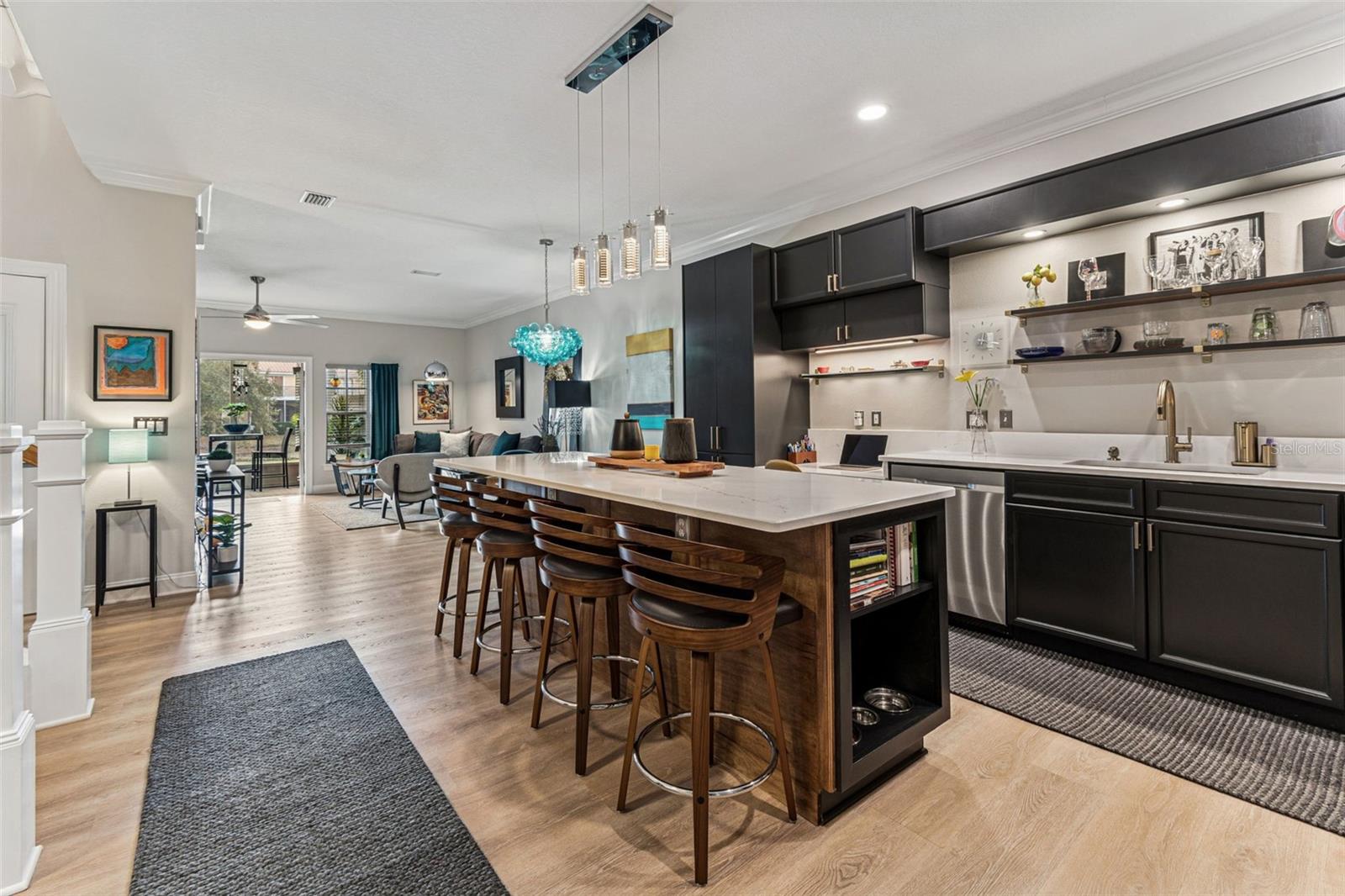 View from front door. Open concept. Clear view to screened porch and pond. Custom quartz counter tops, oversized island that seats 4, open shelves, pet station/books. Built-in quartz desk, pantry for storage.