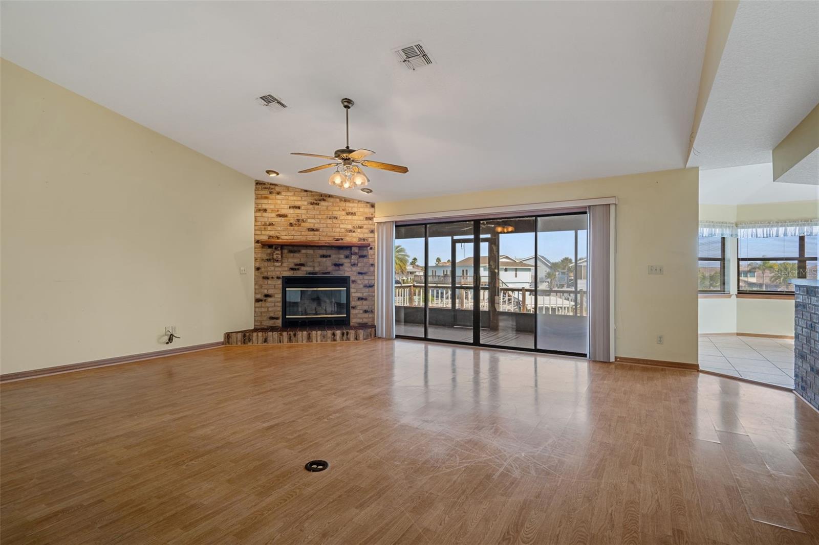 Living Room with Wood Burning Fireplace and Sliders to Lanai Overlooking Canal