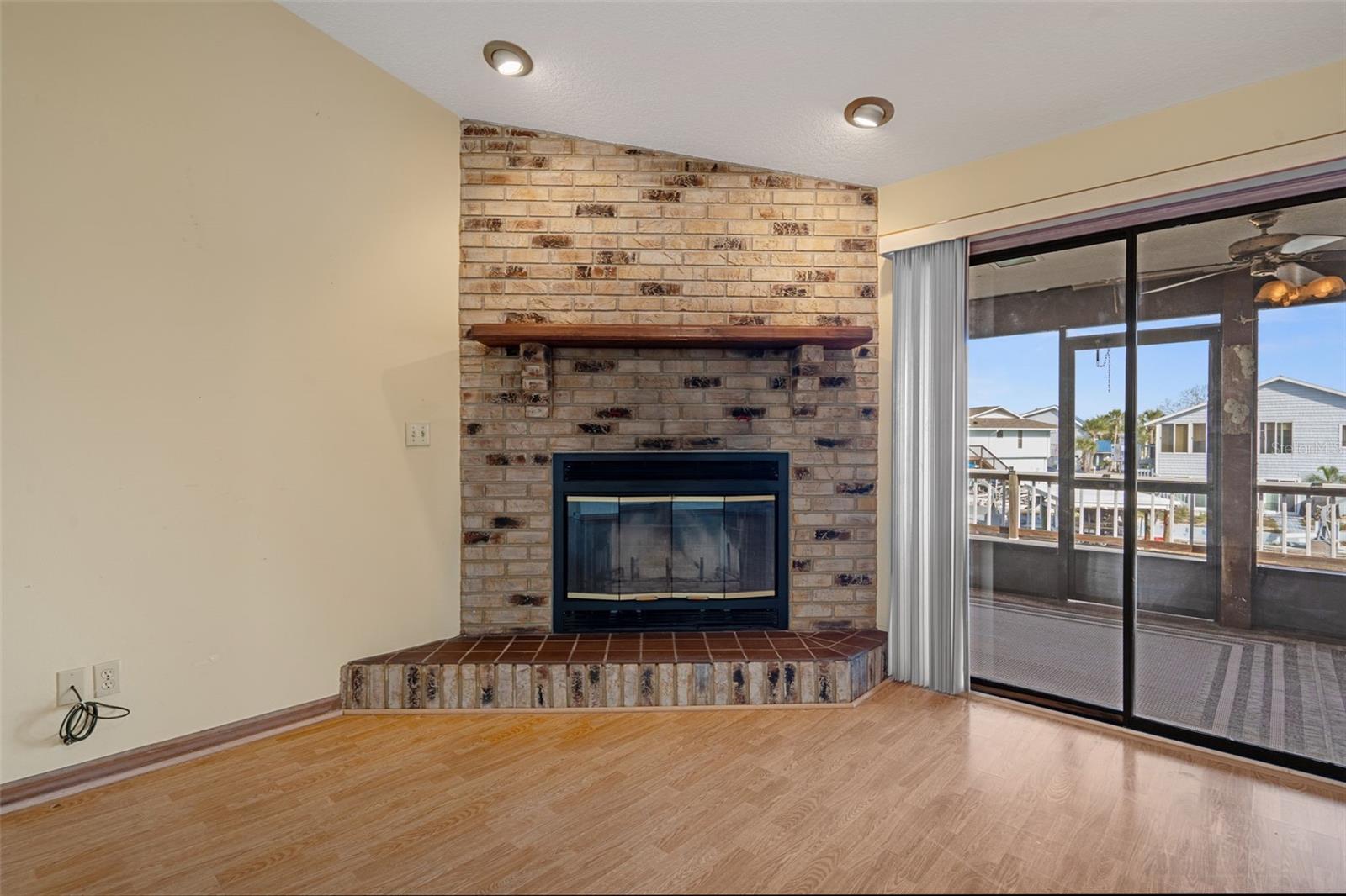 Living Room with Wood Burning Fireplace and Sliders to Lanai Overlooking Canal