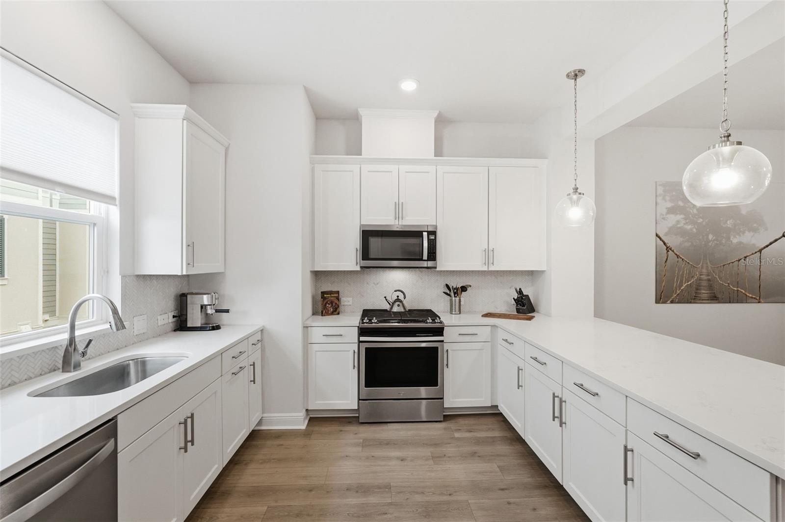 Kitchen includes a gas range, quartz counters, bar seating.