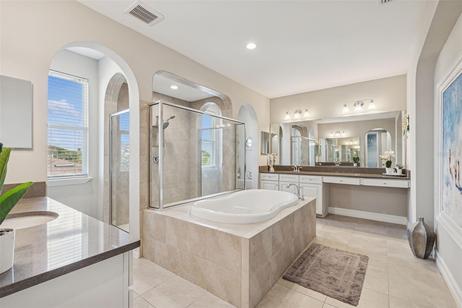 Spa-inspired primary en suite featuring a soaking tub, oversized shower, dual vanities, and generous storage
