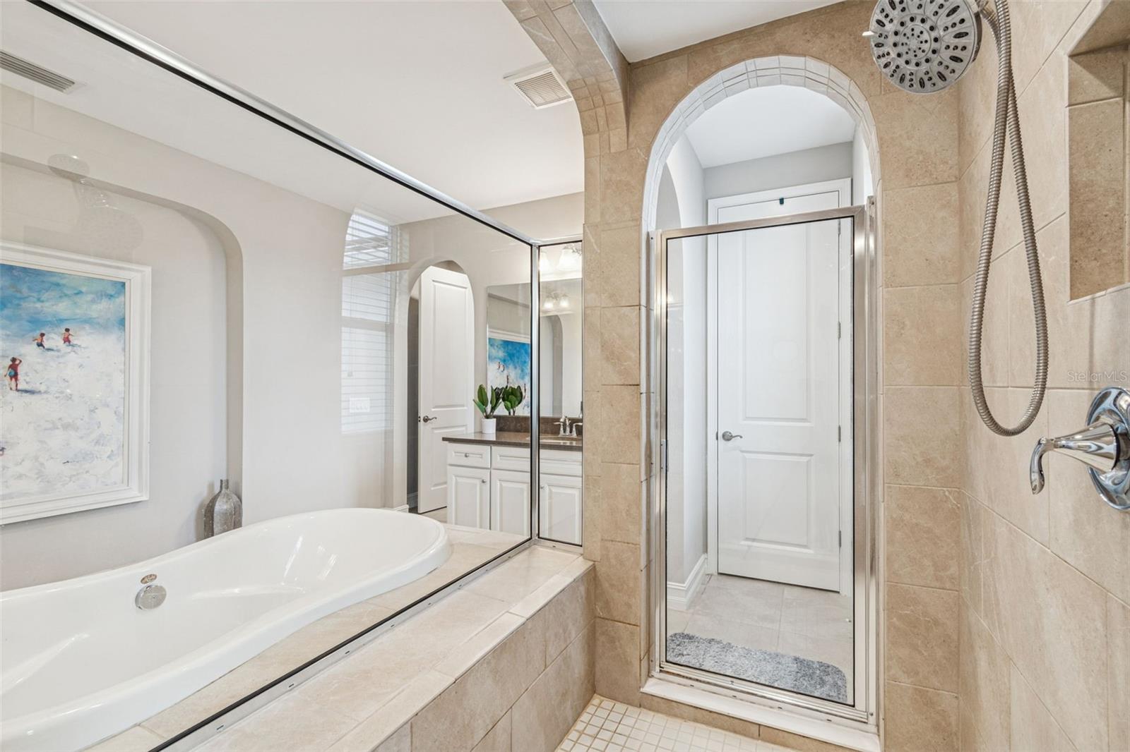 Spa-inspired primary en suite featuring a soaking tub, oversized shower, dual vanities, and generous storage