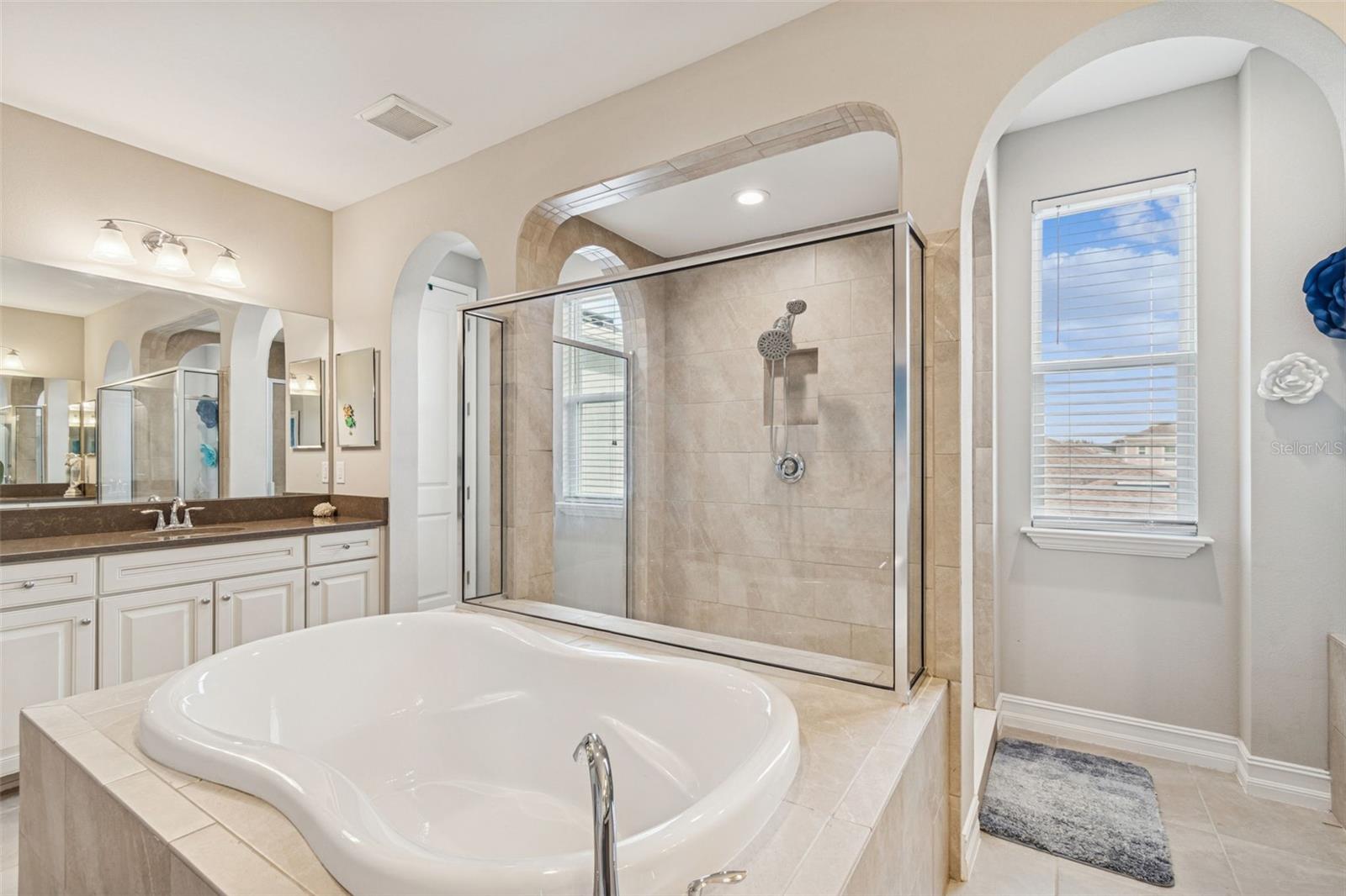 Spa-inspired primary en suite featuring a soaking tub, oversized shower, dual vanities, and generous storage