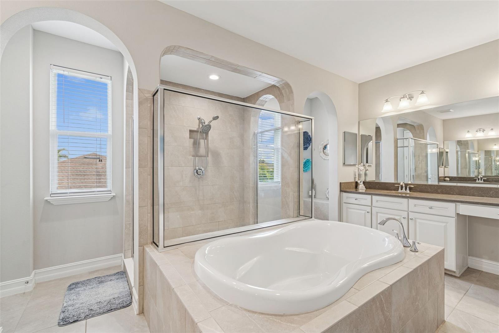Spa-inspired primary en suite featuring a soaking tub, oversized shower, dual vanities, and generous storage