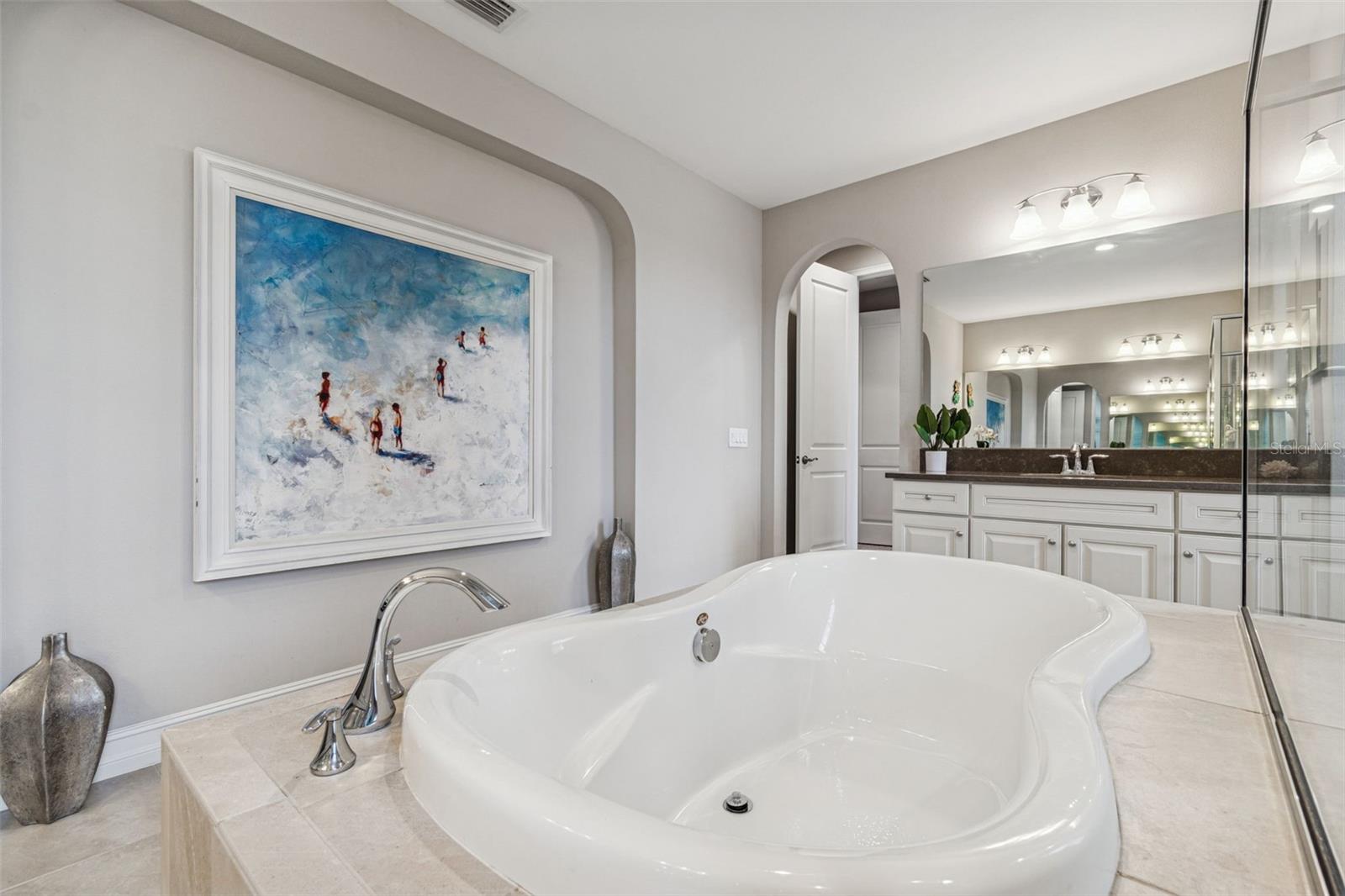 Spa-inspired primary en suite featuring a soaking tub, oversized shower, dual vanities, and generous storage