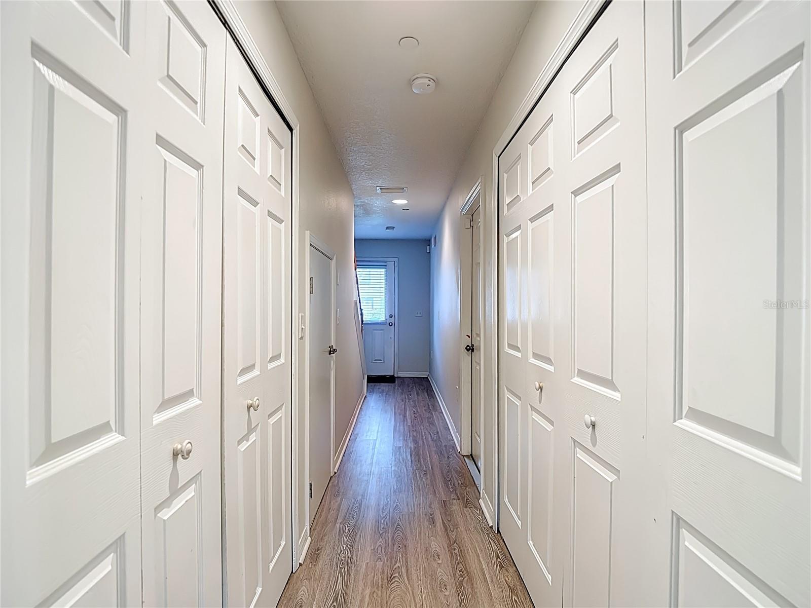 View to Entry from 1st Bedroom, Laundry Closet to Left, Storage and Garage Door to Right.