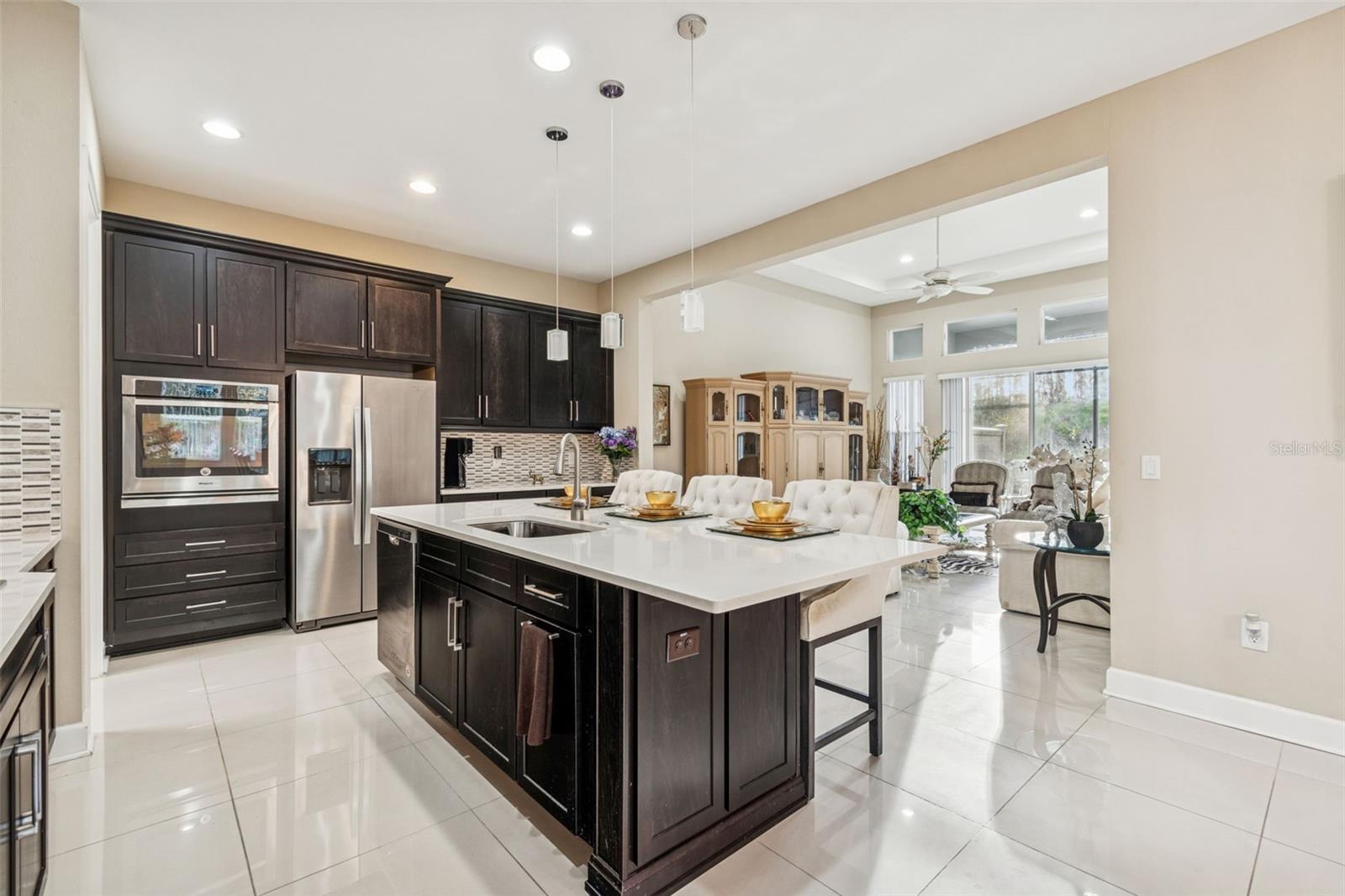 Well-appointed kitchen with quartz countertops, stainless steel appliances, and oversized island with view of living room