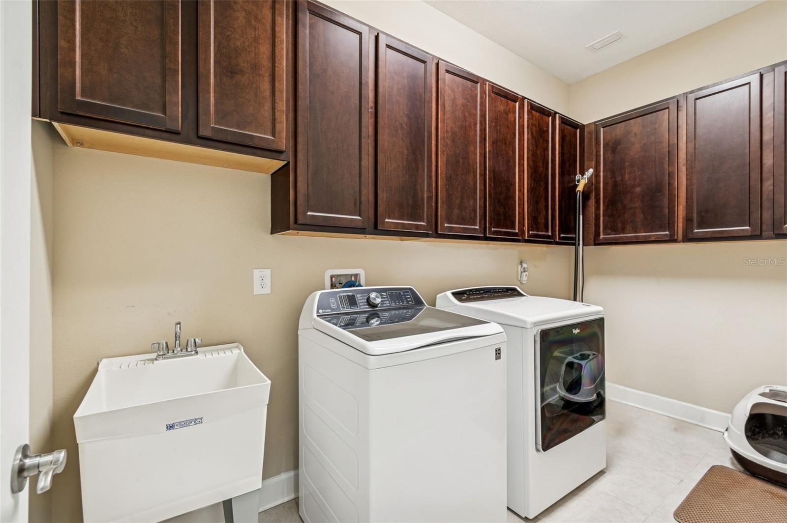 Generously sized laundry room featuring ample cabinetry and utility sink