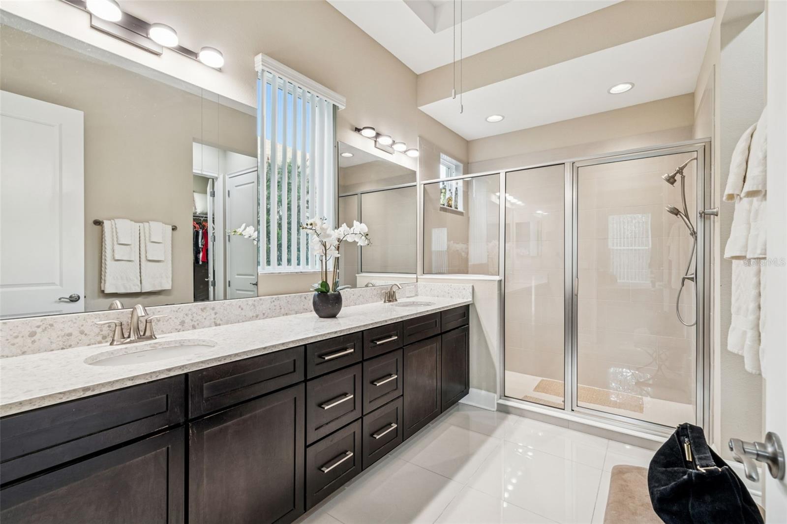 Primary en-suite bath with dual sinks, generous counter space, an oversized walk-in shower and plentiful storage.