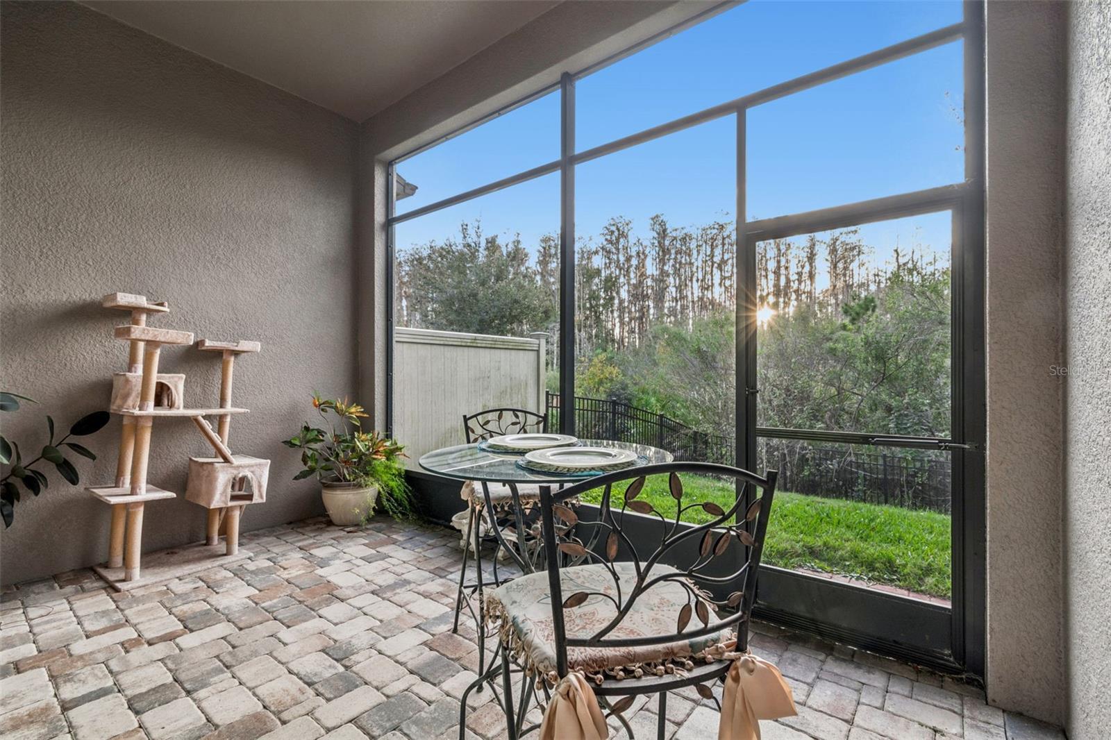 Private pavered screened-in patio with access to the fenced backyard