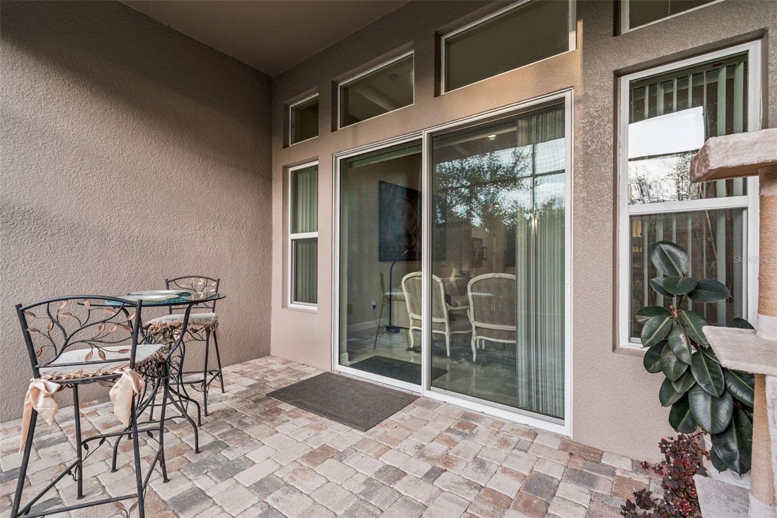 Private pavered screened-in patio with access to the fenced backyard