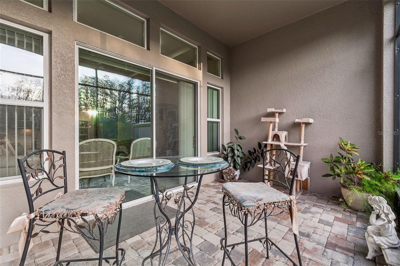 Private pavered screened-in patio with access to the fenced backyard