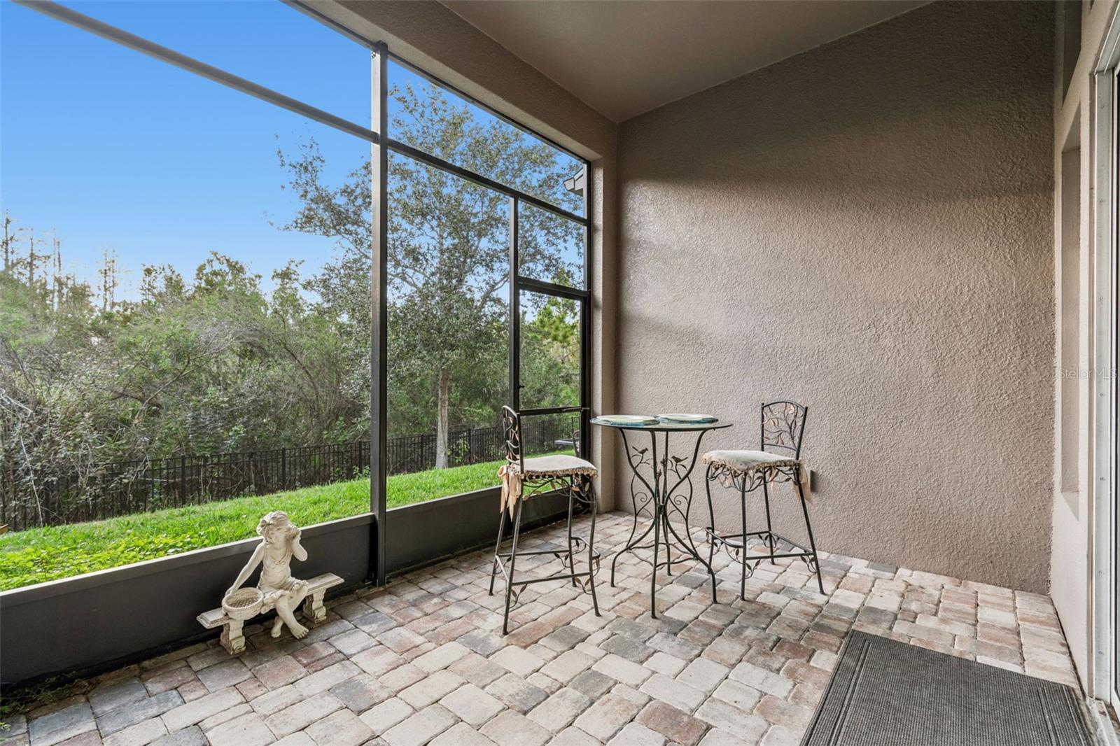 Private pavered screened-in patio with access to the fenced backyard