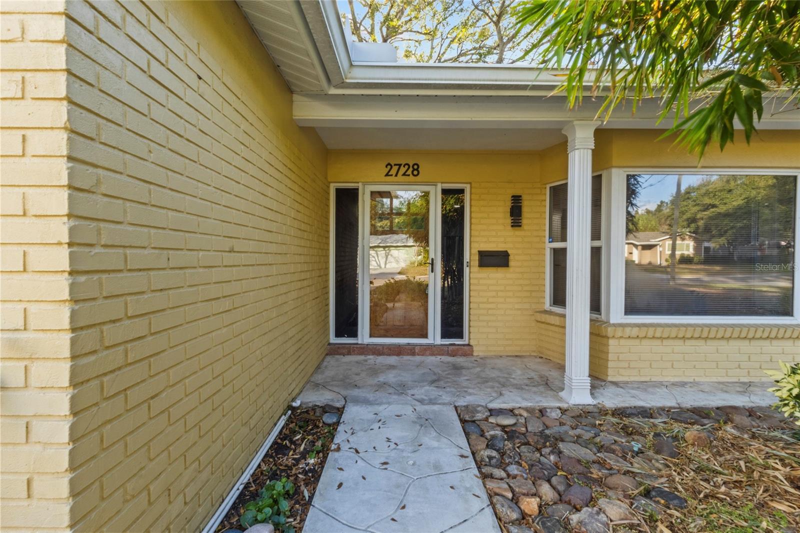 Inviting covered entry with brick exterior and clean architectural lines, welcoming you into this well-maintained home.