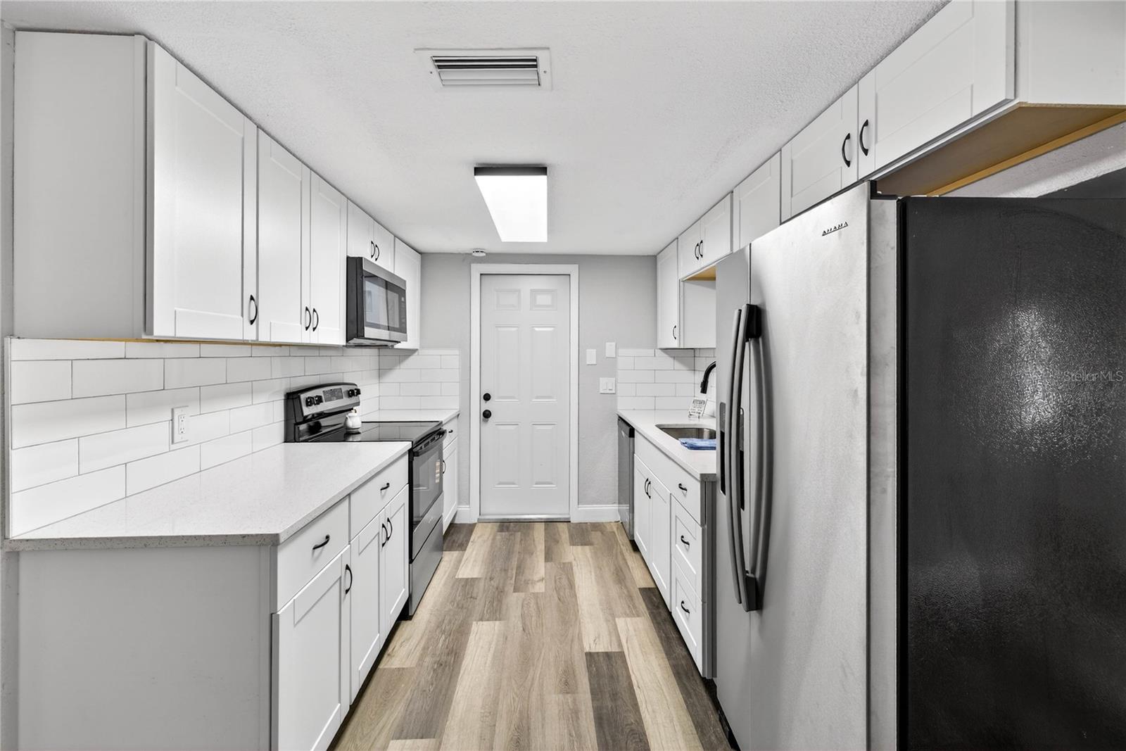 REMODELED KITCHEN WITH SHAKER STYLE CABINETS AND QUARTZ COUNTERTOPS. ENTRANCE TO THE GARAGE STRAIGHT AHEAD