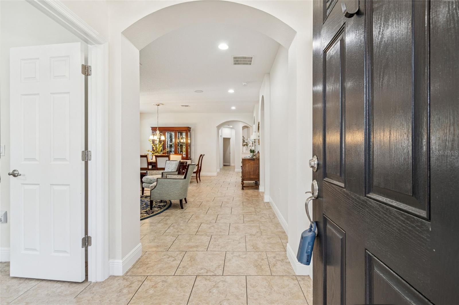 An inviting foyer with tile flooring and graceful arched openings that lead into a bright, open living and dining space beyond.