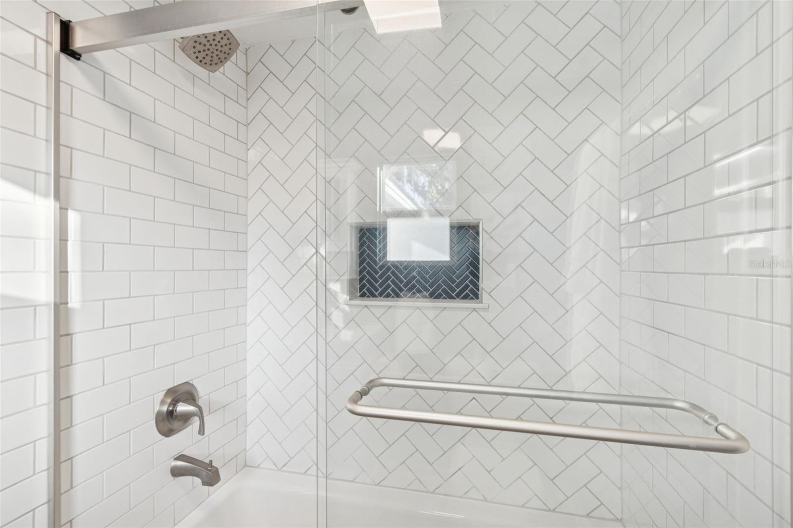 New Kohler cast iron tub surrounded by subway tile and sliding glass door enclosure.