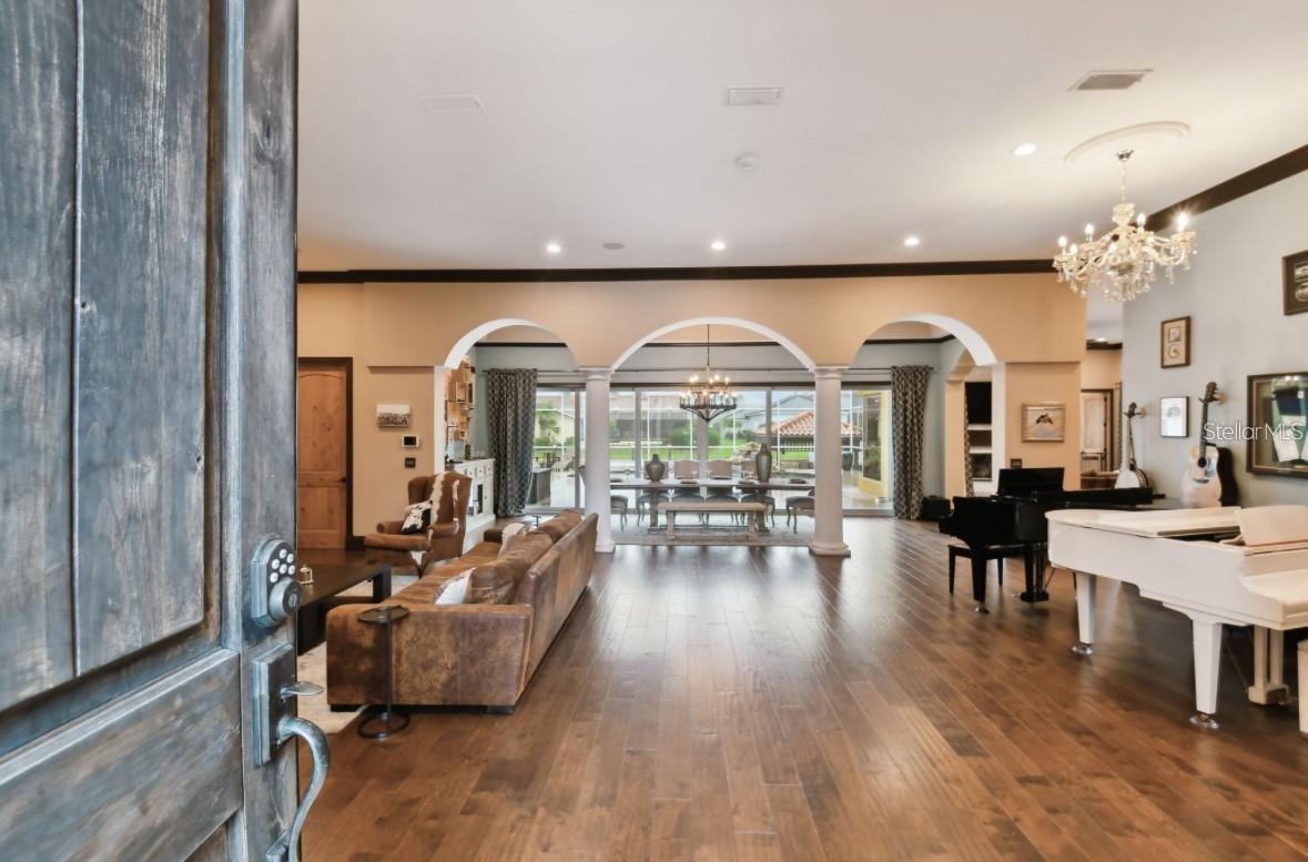 front door through living room, dining room looking out towards pool