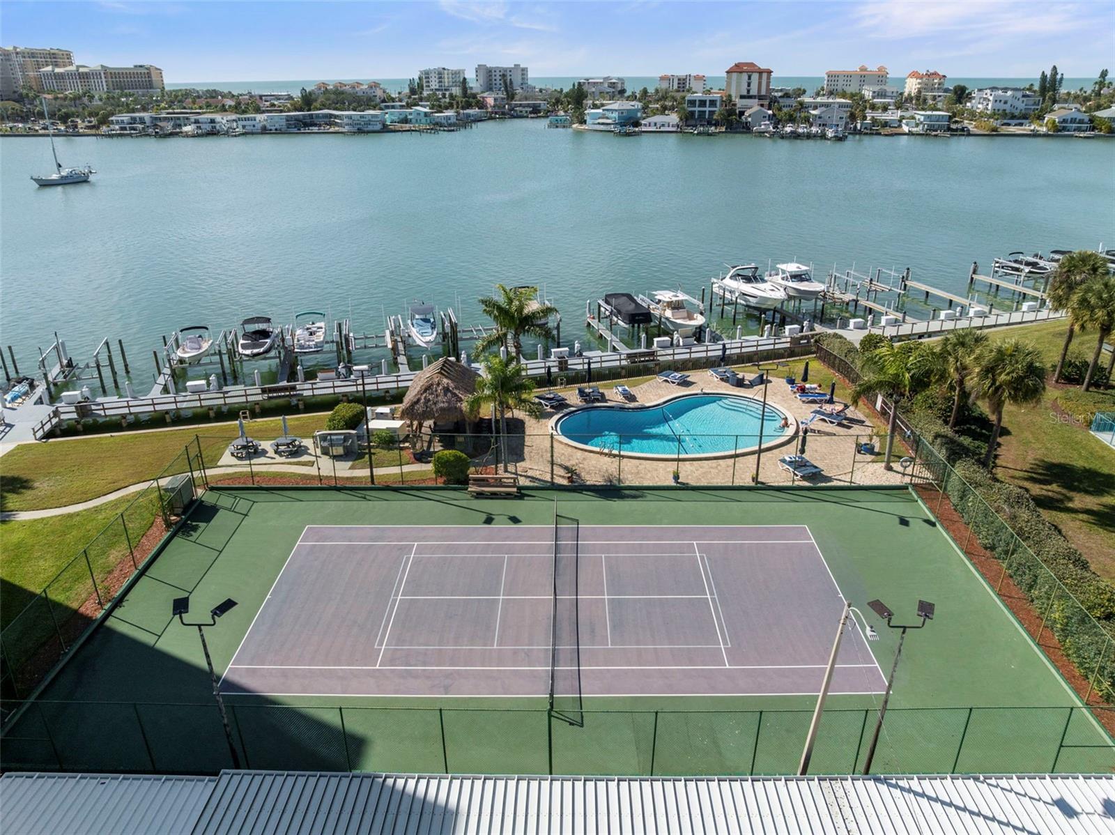 You may rarely go inside your condo with all the amenities to enjoy both outside and on the lower level of the building.  Here you see the tennis/pickleball court, pool, tiki hut, picnic area, grilling area and boat docks. Docks are rented separately.