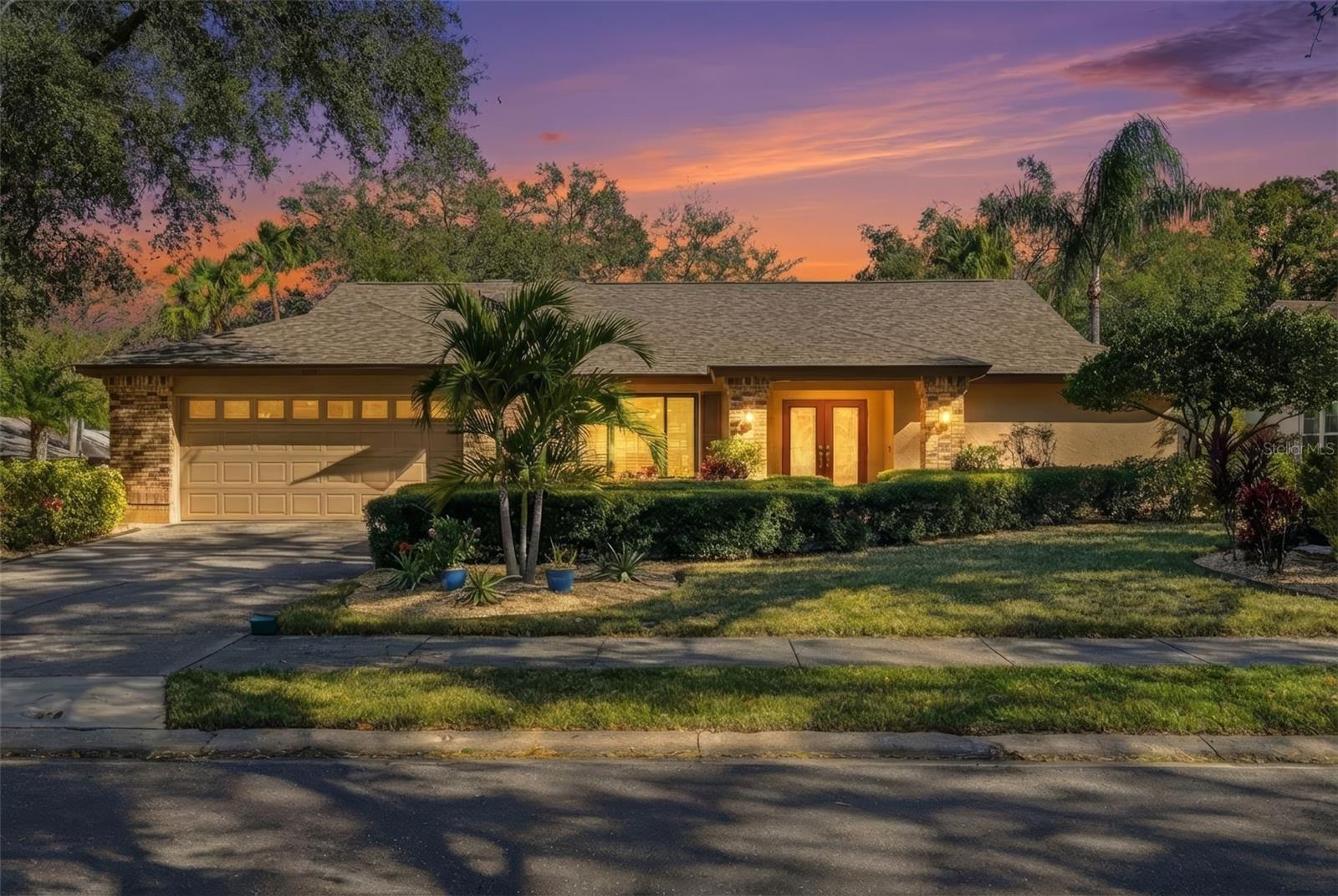 Front view of the garage and double door entrance.  New Palm trees, sod and rock.