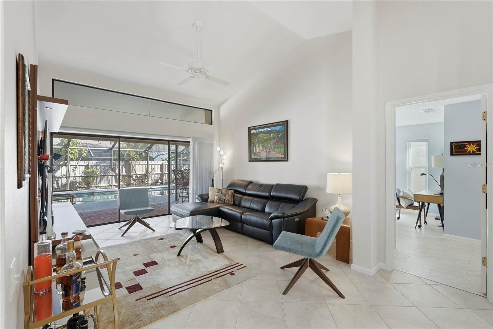 Living room with new motorized shade with built in privacy curtain and entrance to the primary bedroom.