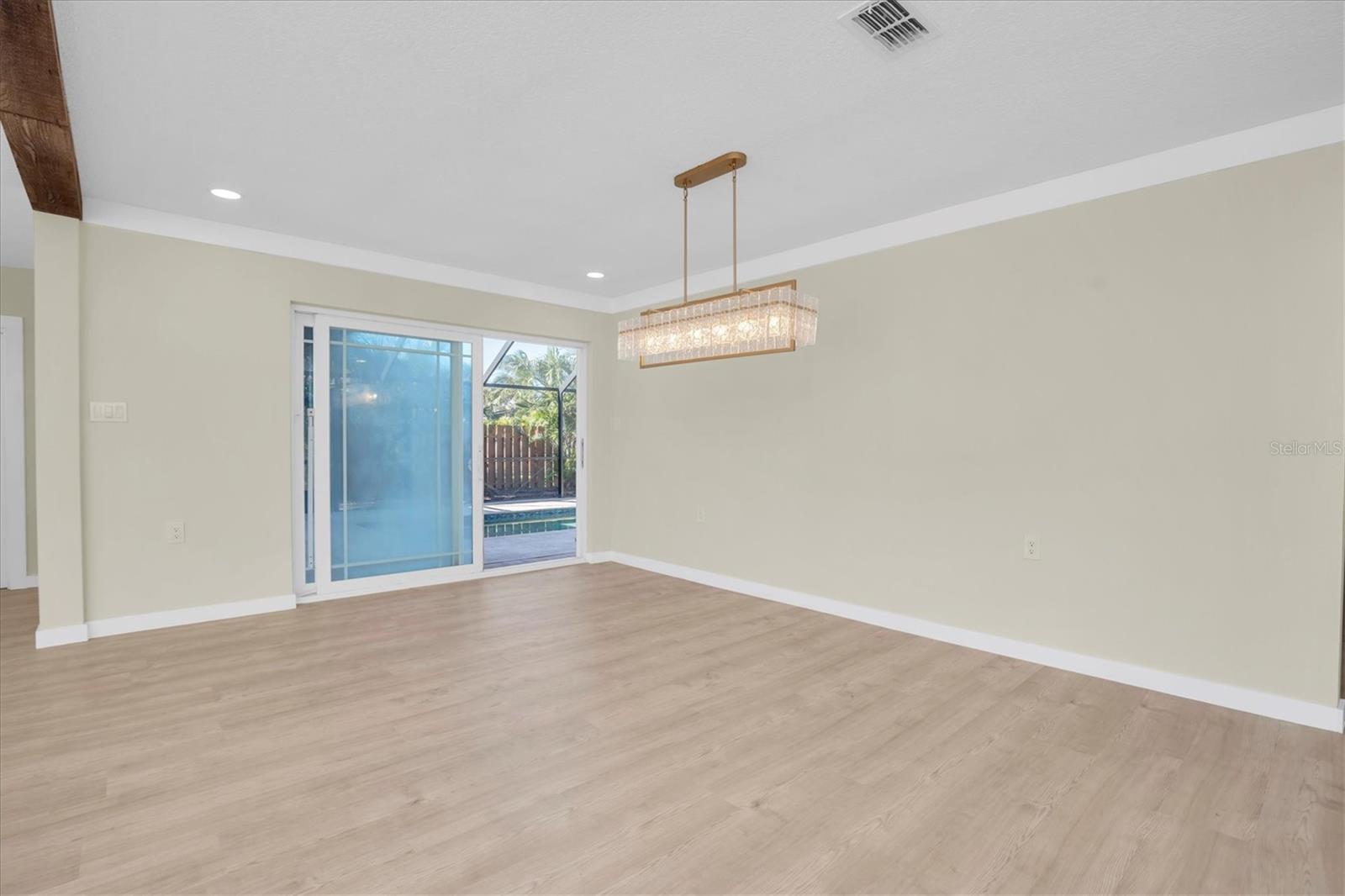 Sliding doors offer effortless access to the screened, enclosed pool, extending the home’s elegant indoor & outdoor living experience.