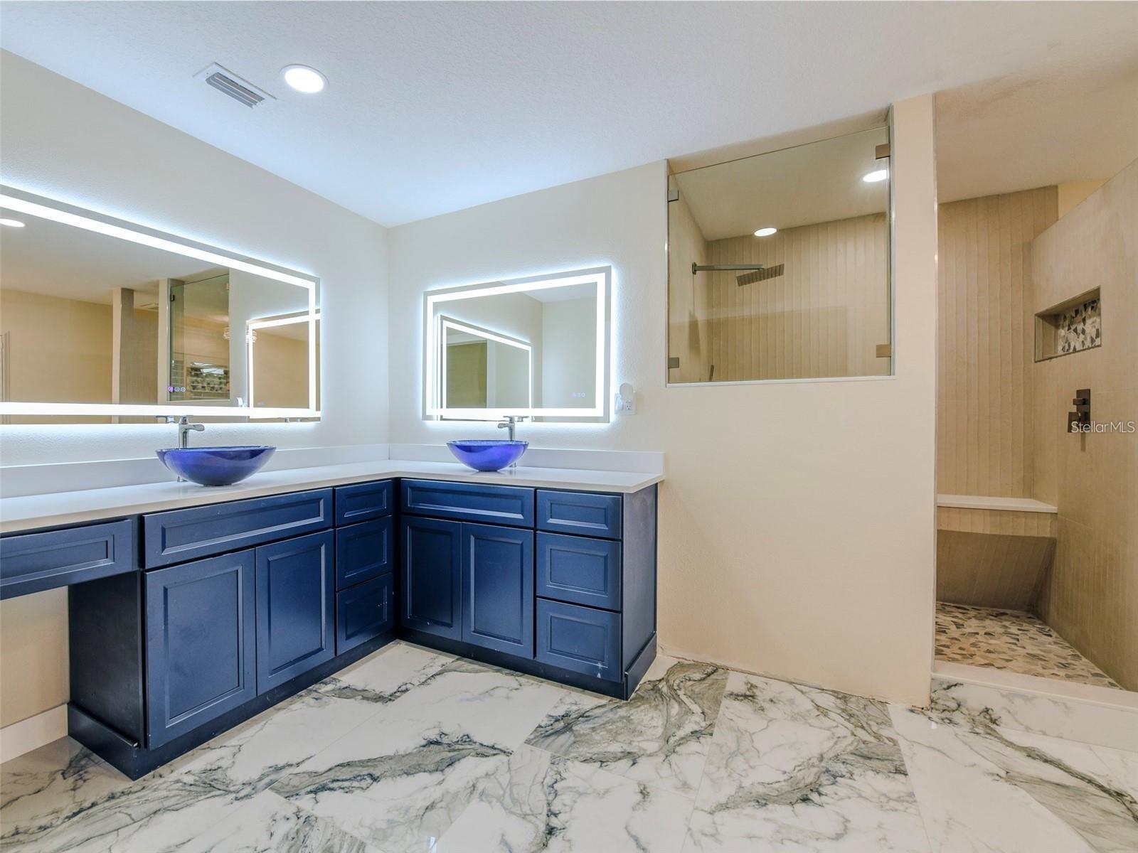 The primary ensuite is appointed with sculptural glass vessel double sinks & sophisticated LED mirrors, elevating the space with a truly luxurious aesthetic.