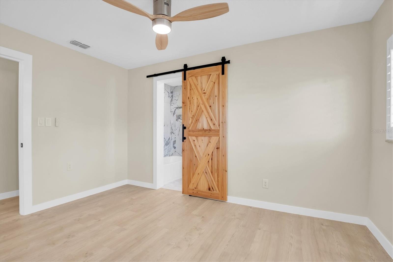 The second bedroom is appointed with stylish barn-style doors that gracefully lead into the gorgeous Jack-and-Jill bathroom.