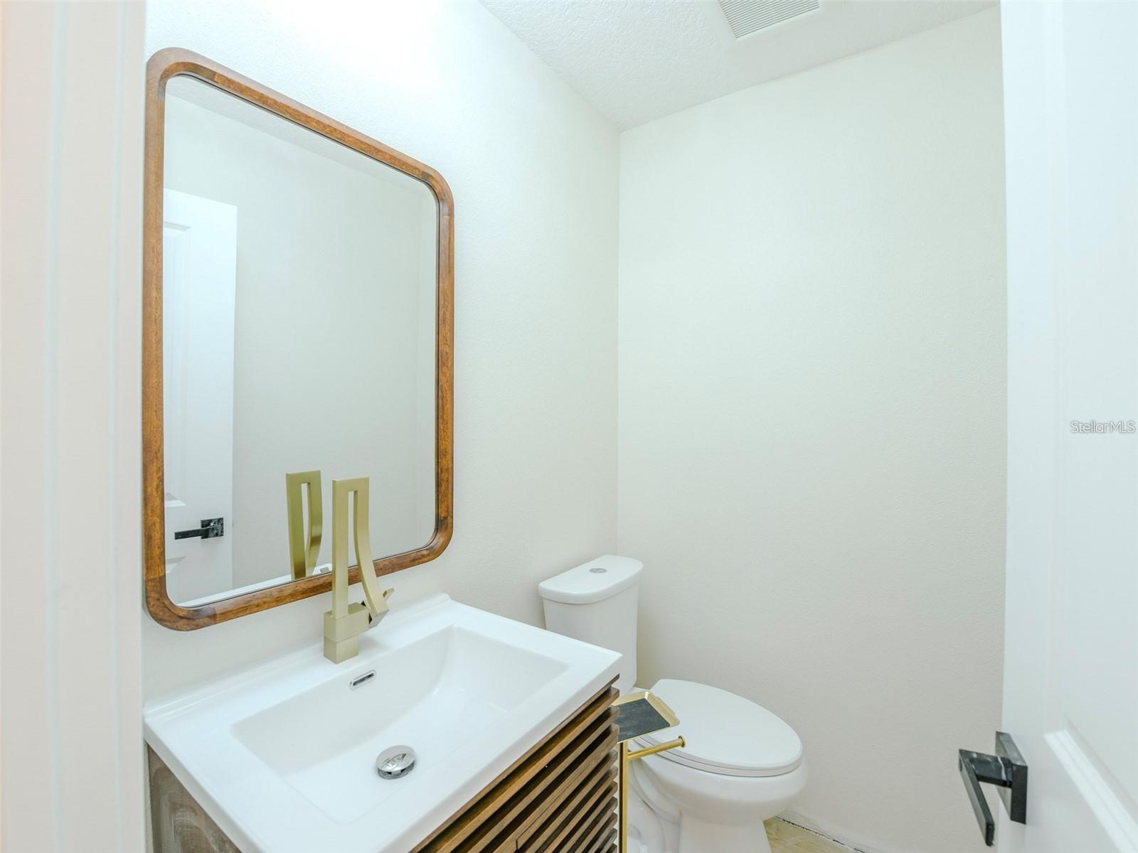 The guest bathroom features a premium faucet, refined cabinetry & a sleek mirror.
