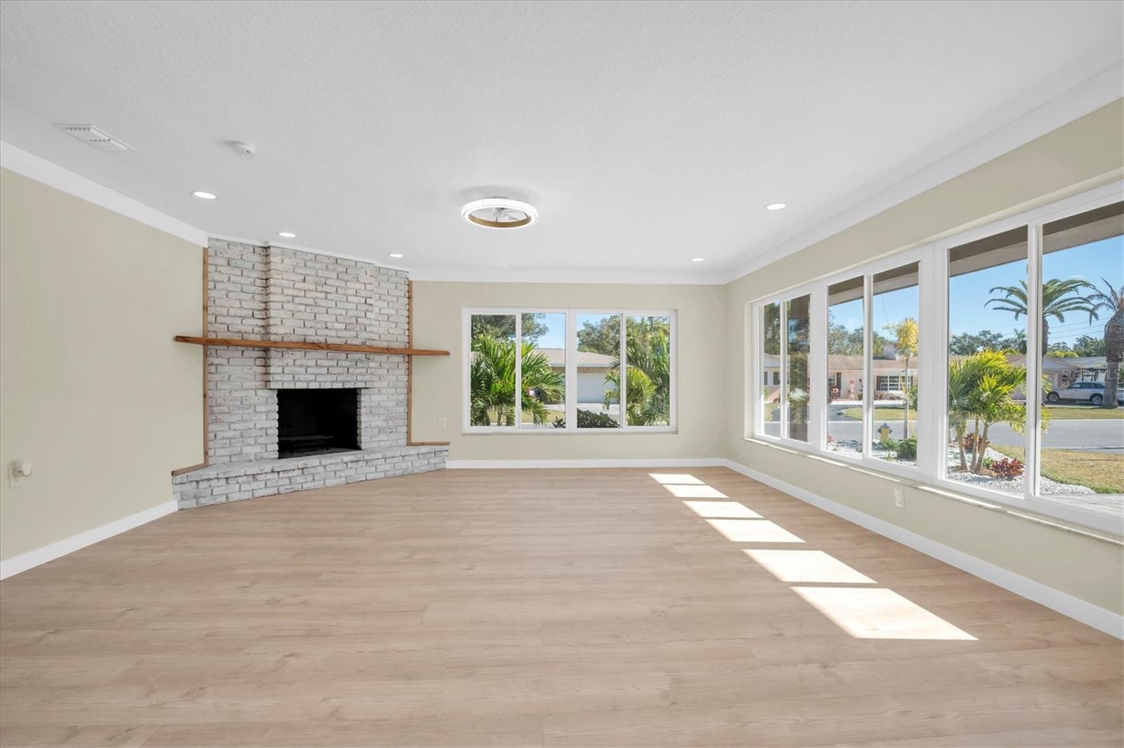 Abundant natural light fills the living room through double-pane windows, complemented by a timeless wood-burning fireplace.
