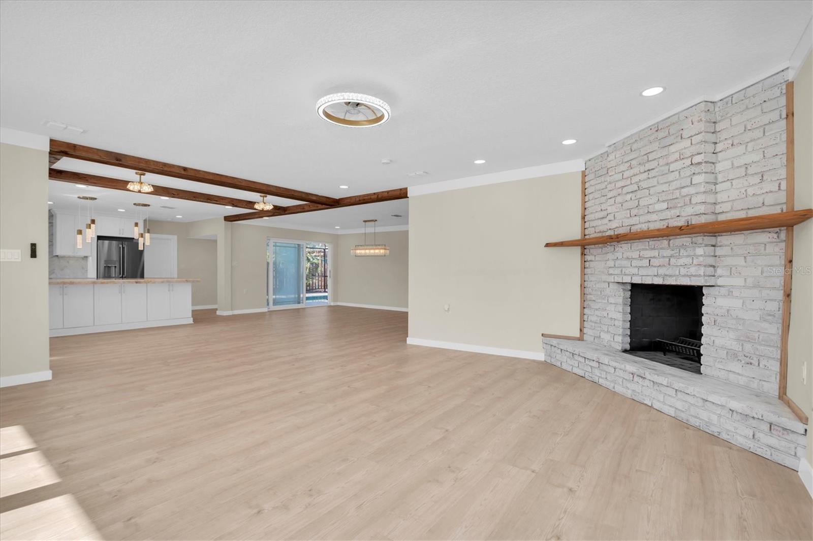 The open layout transitions gracefully into the kitchen, enhanced by bold, architectural ceiling beams.