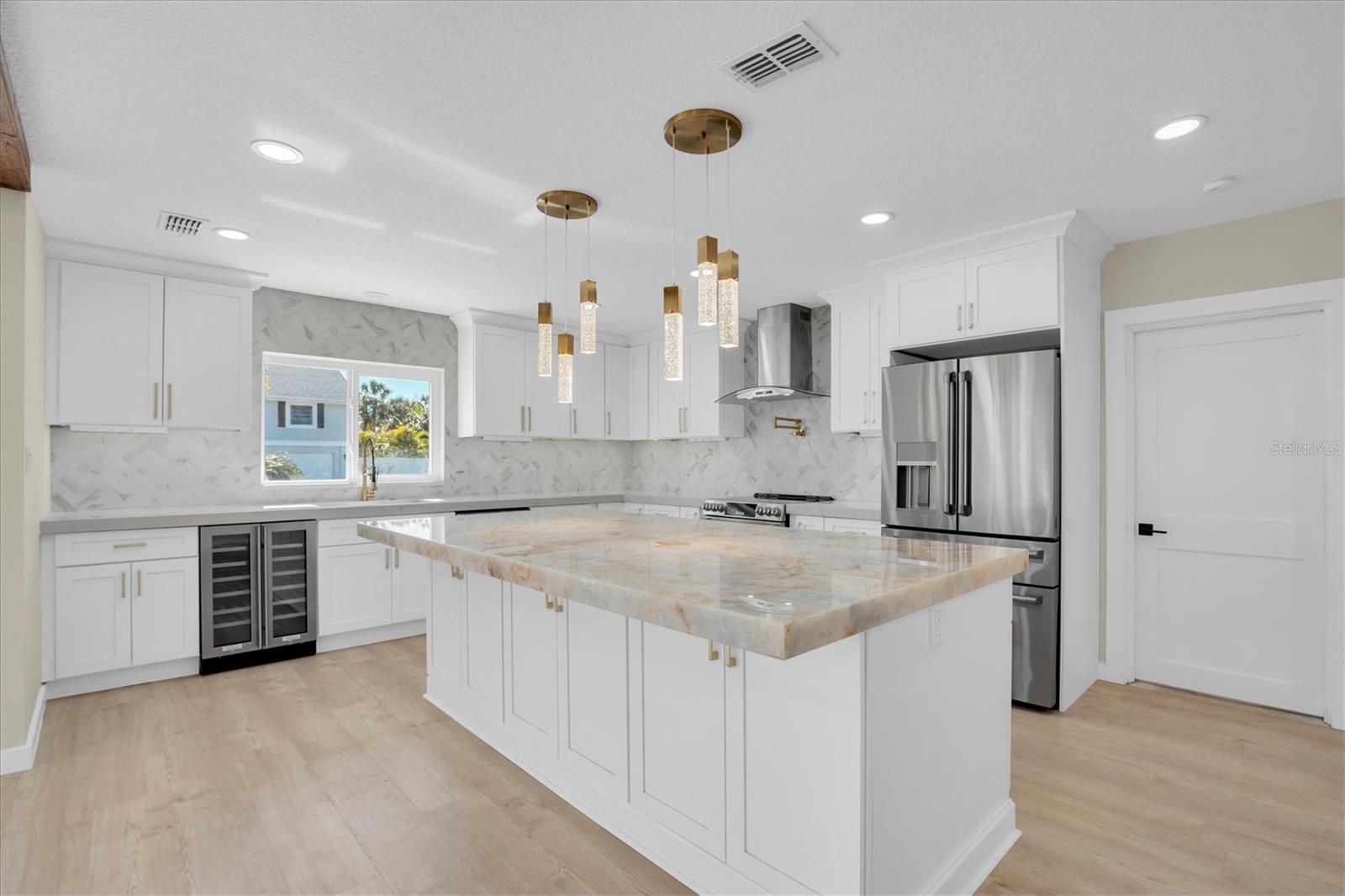 The expansive kitchen features a dramatic center island with undermount lighting, complemented by illuminated cabinetry; perfect for grand entertaining.