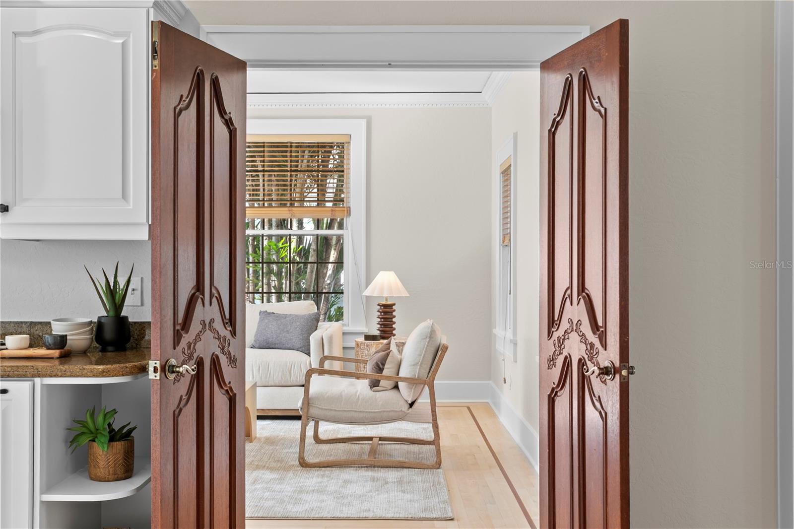Peak from the kitchen into the light and open sunroom with French doors to the backyard