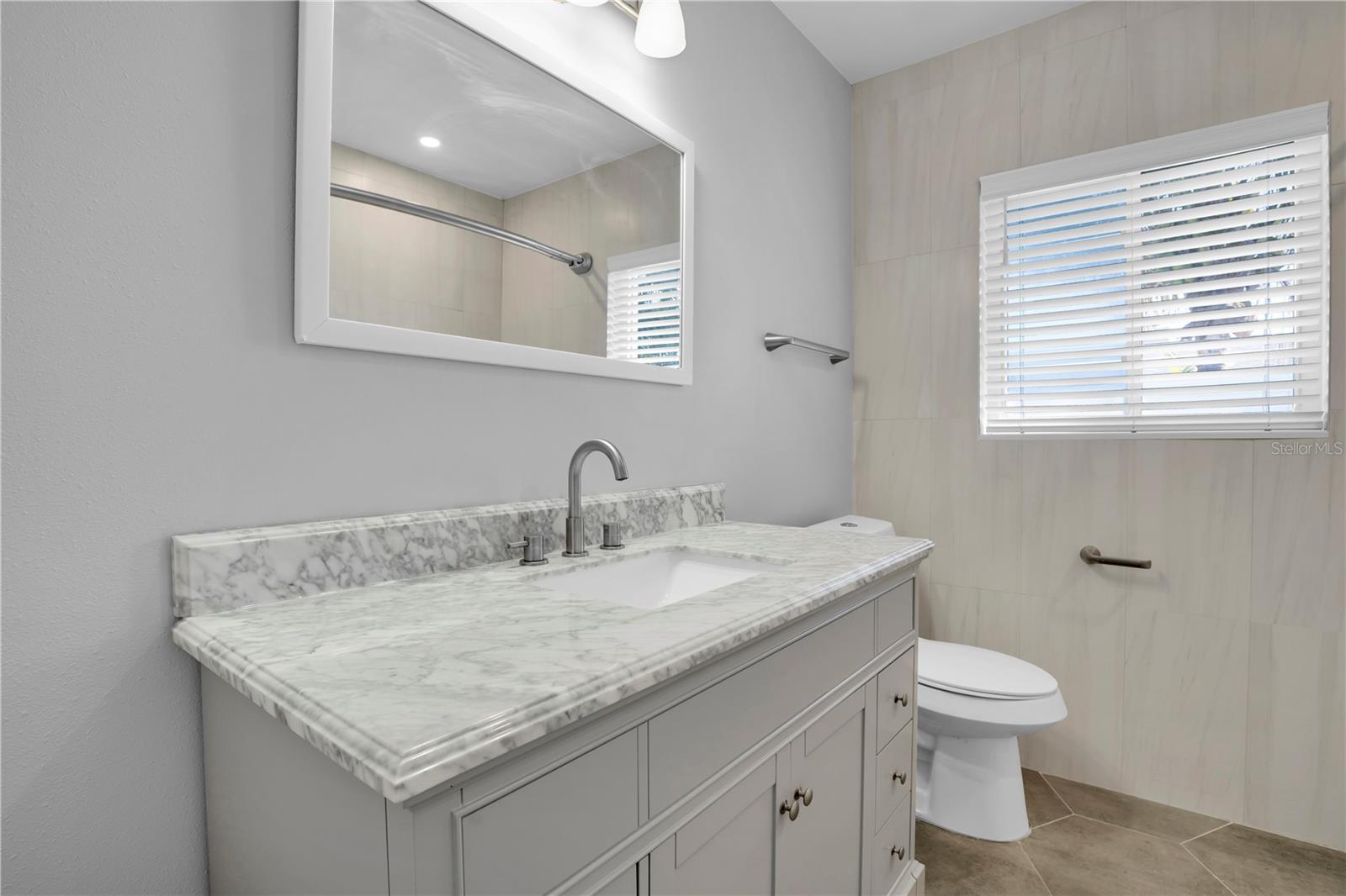 This inviting full bathroom, featuring a soothing tub and a refreshing shower, provides a delightful shared retreat for the residents of bedrooms 2 and 3.