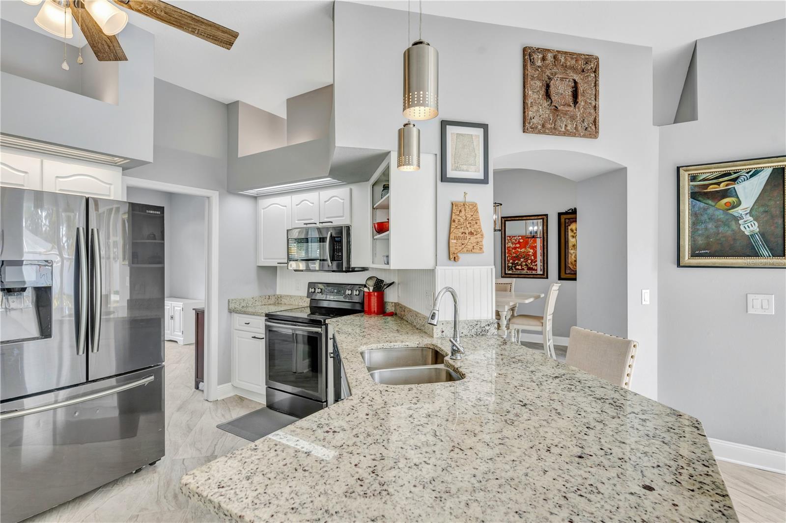 The kitchen features granite countertops and sleek dark stainless steel appliances.
