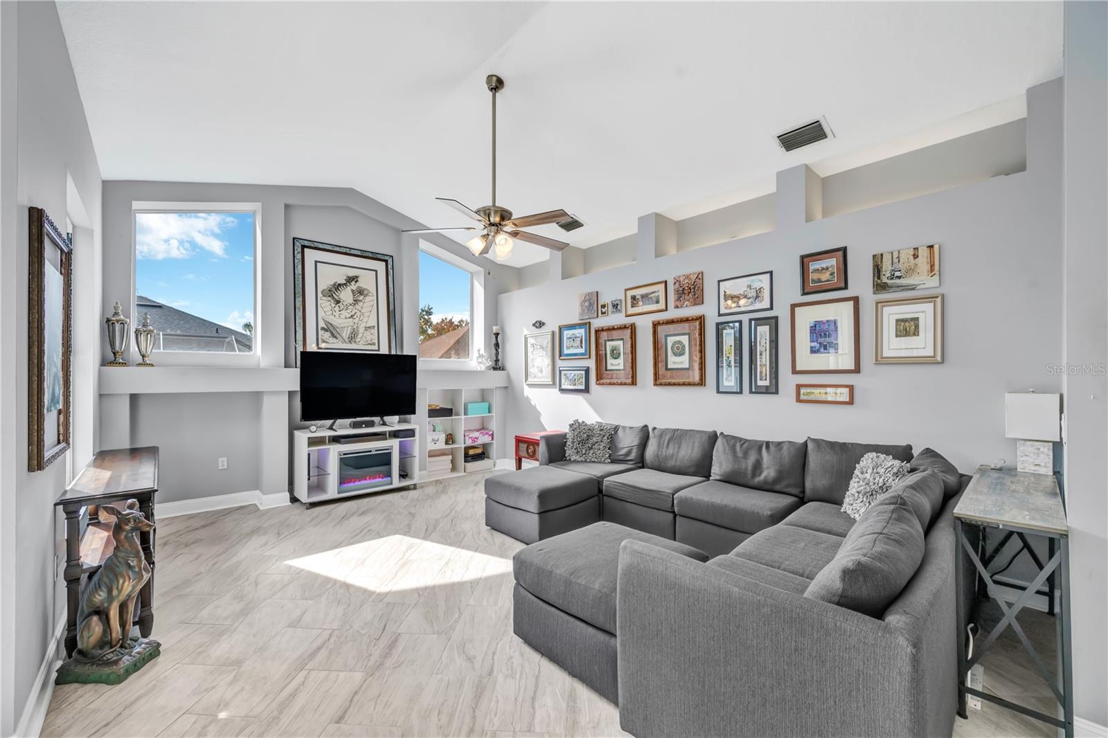 The light-filled family room showcases soaring ceilings, south-facing windows, and custom built-in shelving and accent lighting above perfect for relaxing or hosting guests.
