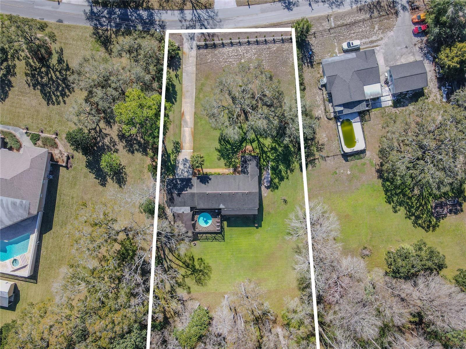 Aerial view highlighting the expansive 1.7-acre parcel, with clearly defined boundaries and a private setting backing to wooded acreage.