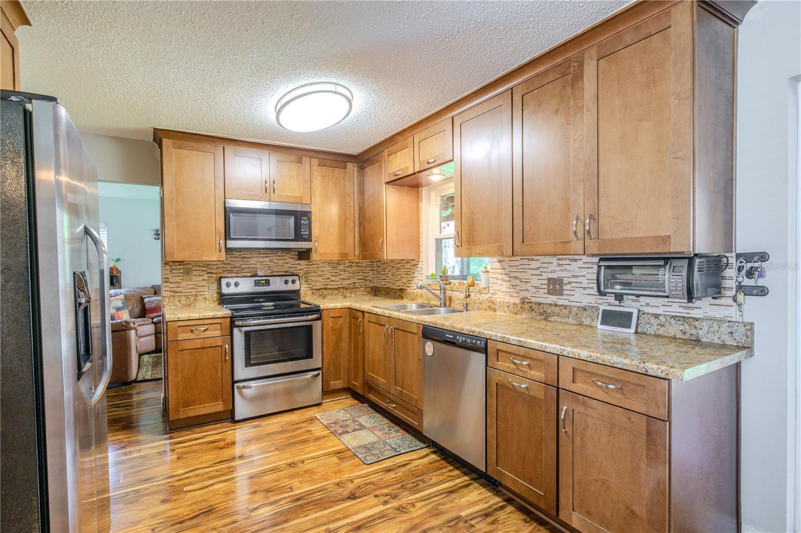 Kitchen view highlighting the full appliance package, extensive cabinet storage, and continuous laminate flooring that carries seamlessly into the adjacent living areas.
