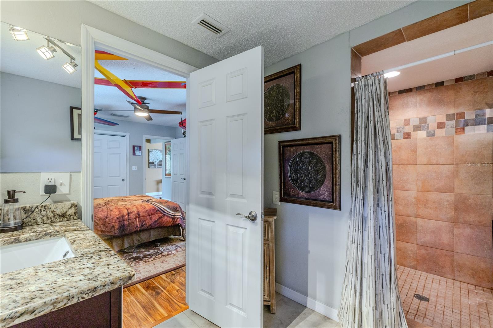 Primary en suite bath featuring a granite-topped vanity, neutral finishes, and a seamless connection to the bedroom for added privacy and convenience
