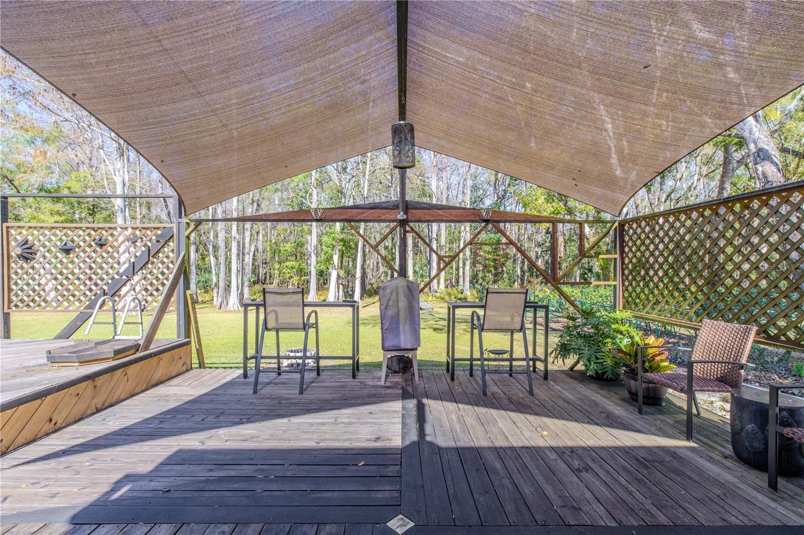 Shaded deck area framed by lattice panels and wood supports, offering an open yet protected outdoor space overlooking the backyard.