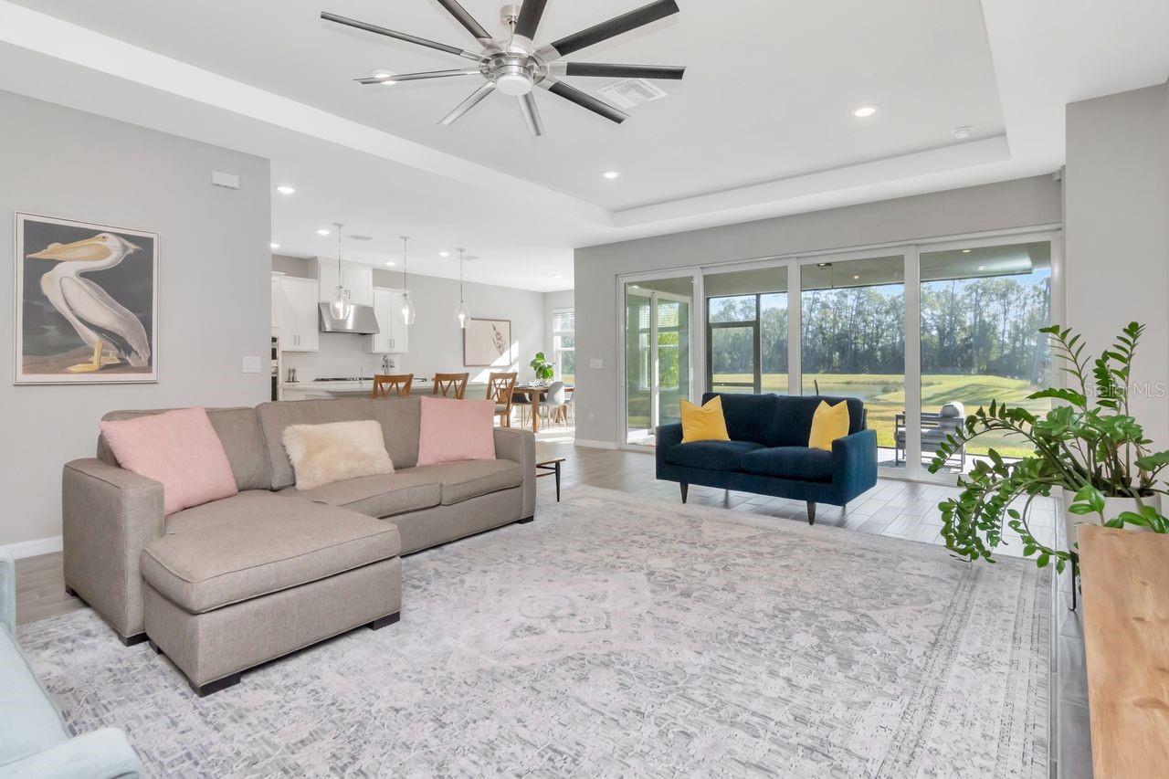 Spacious Livingroom with tray ceiling, upgraded ceiling fan and fantastic views through the panoramic sliding glass doors.